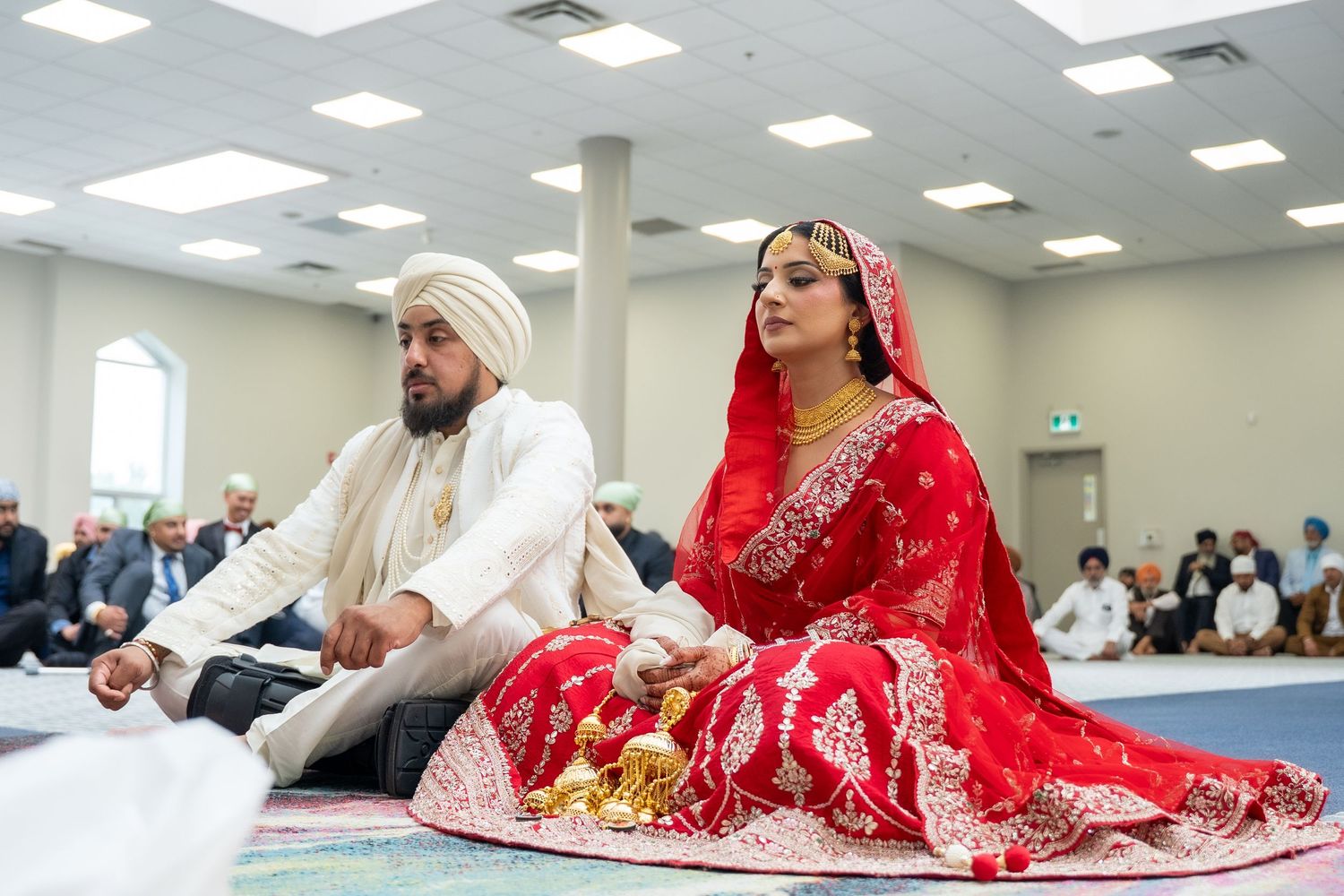 A traditional Muslim wedding ceremony takes place in a bright indoor venue with guests seated in rows.