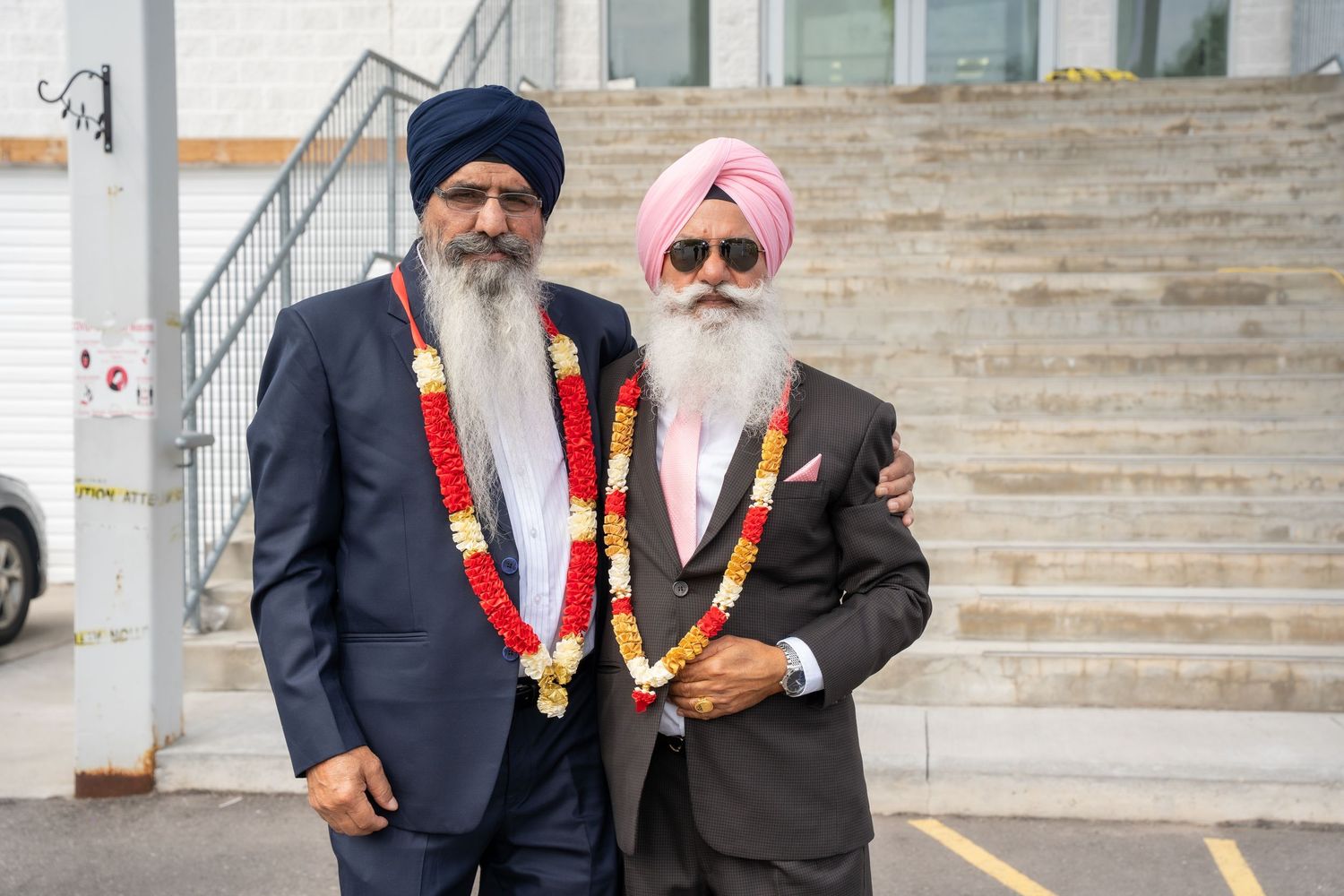 A group wearing traditional Sikh attire standing on stone steps at a formal event.