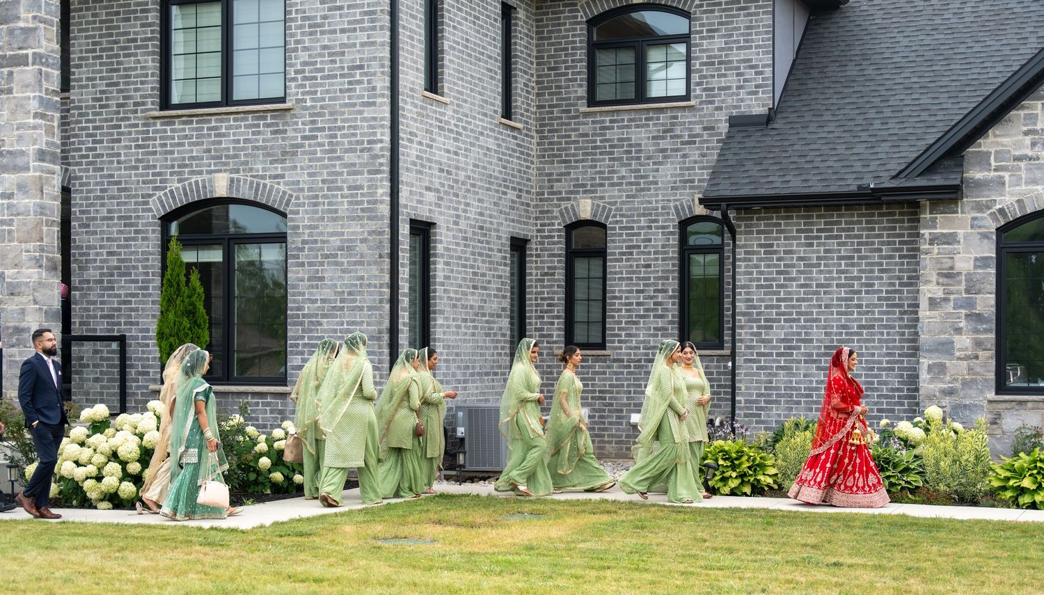 A panoramic view of modern gray brick townhouses with landscaped front yards and walkways.