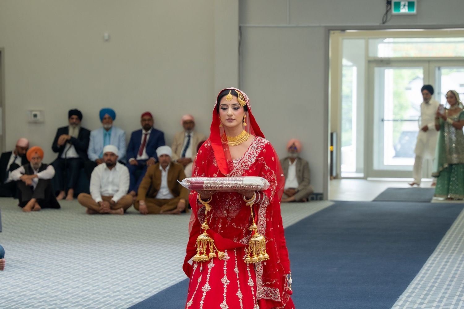 A bride in a traditional red and gold Indian wedding lehenga poses elegantly during her ceremony.