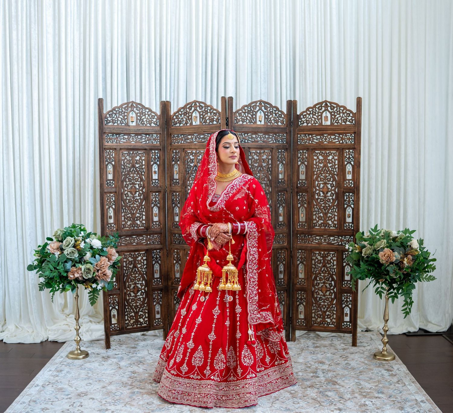 A bride in a vibrant red and gold embroidered lehenga is photographed in multiple poses with decorative screens.