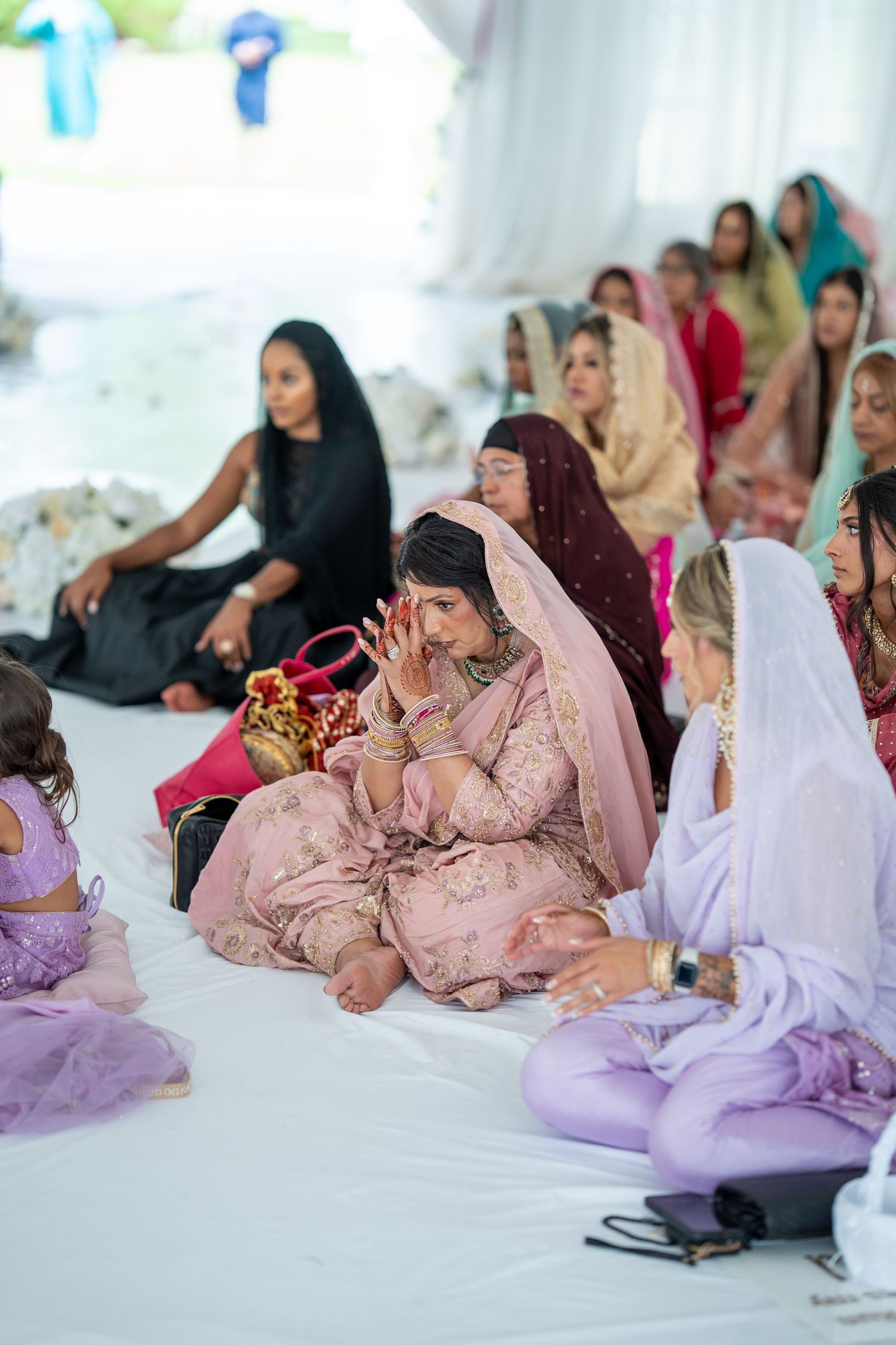 Wedding guests seated on floor cushions during a traditional Sikh ceremony.