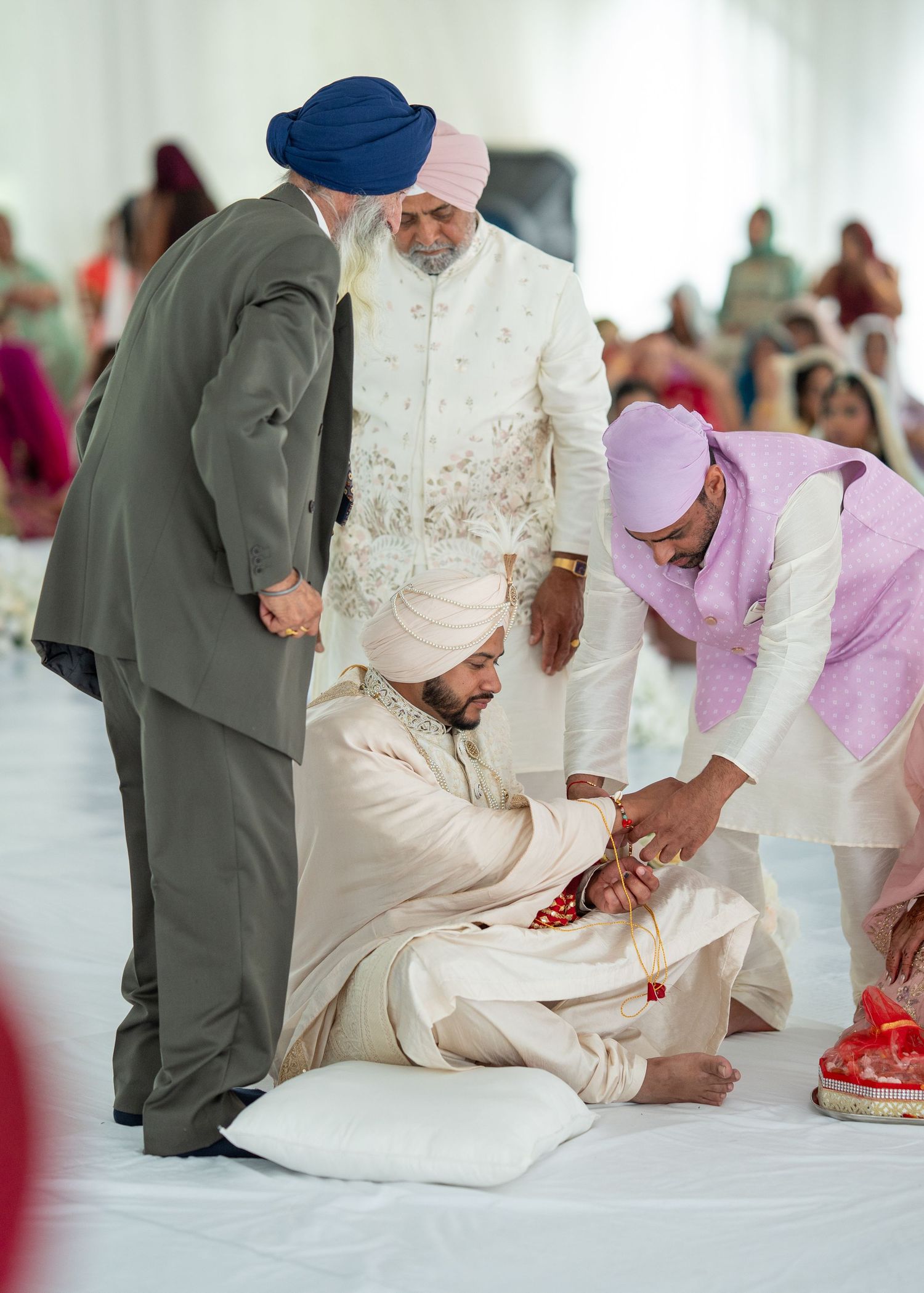 Traditional Sikh wedding ceremony showing guests seated on the floor during religious rituals.