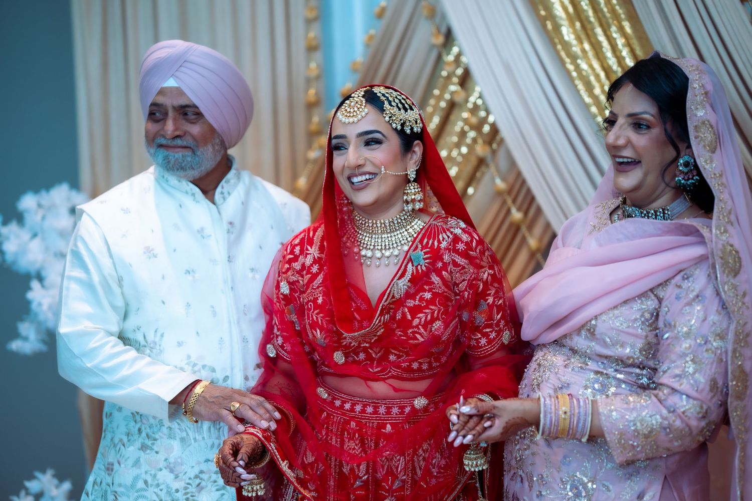 A joyful wedding celebration with the bride in a traditional red lehenga accompanied by family members at the ceremony.