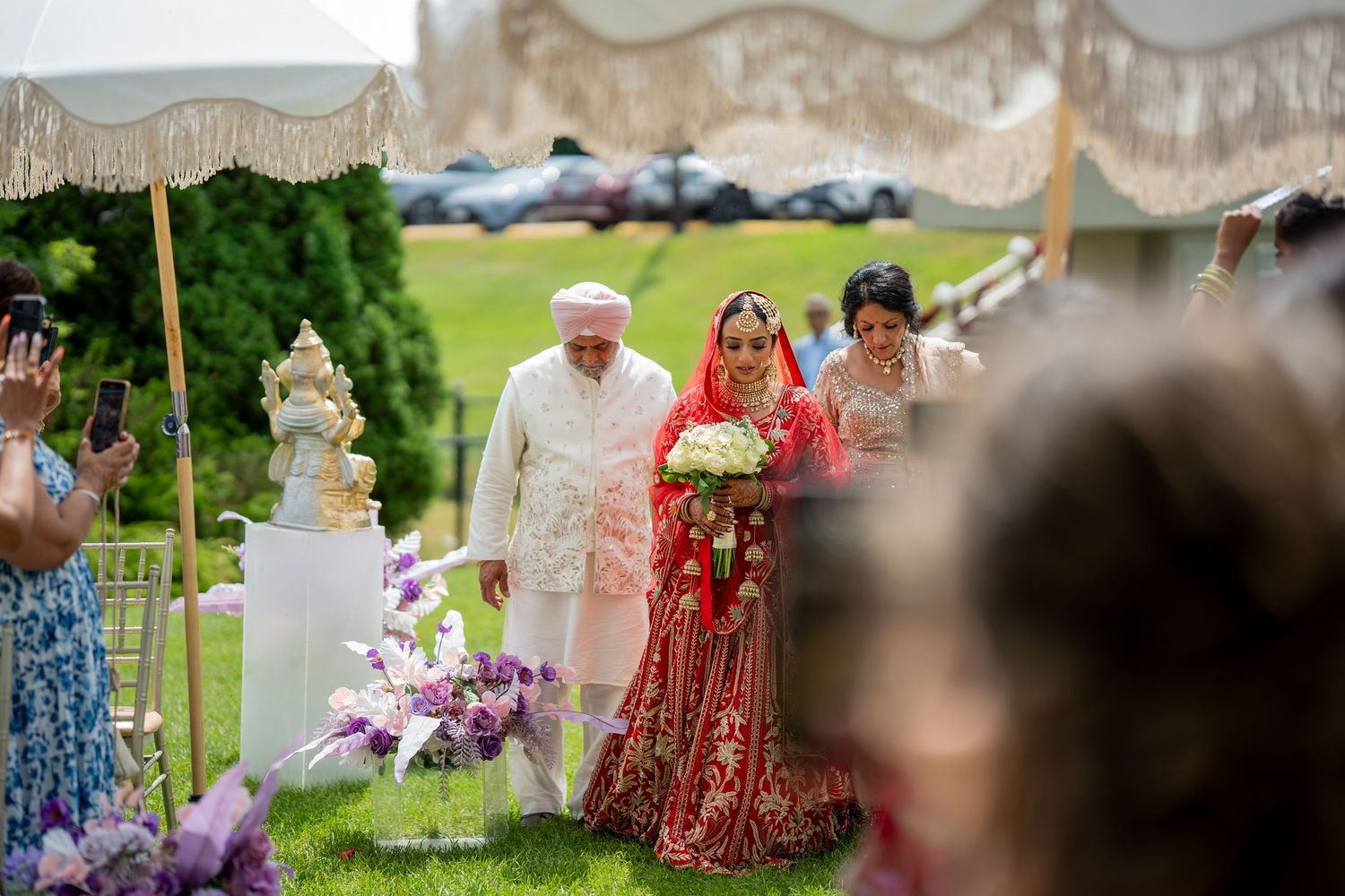 Outdoor wedding ceremony setup with floral decorations and guests seated under a canopy.