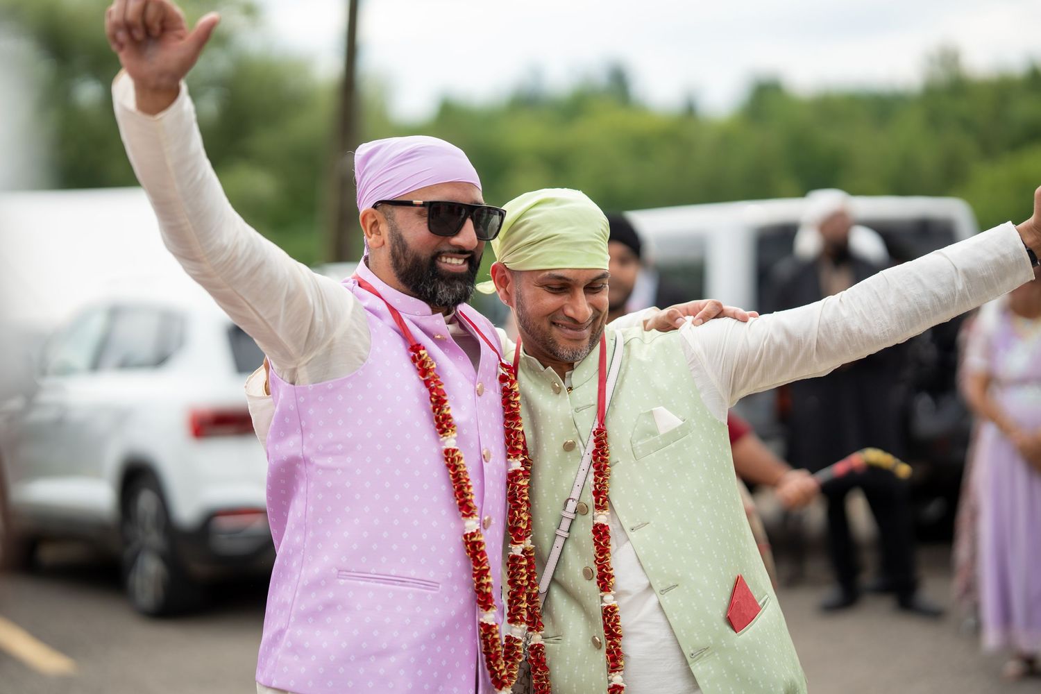 Joyful outdoor wedding celebration with guests in traditional Indian and Western attire dancing together.