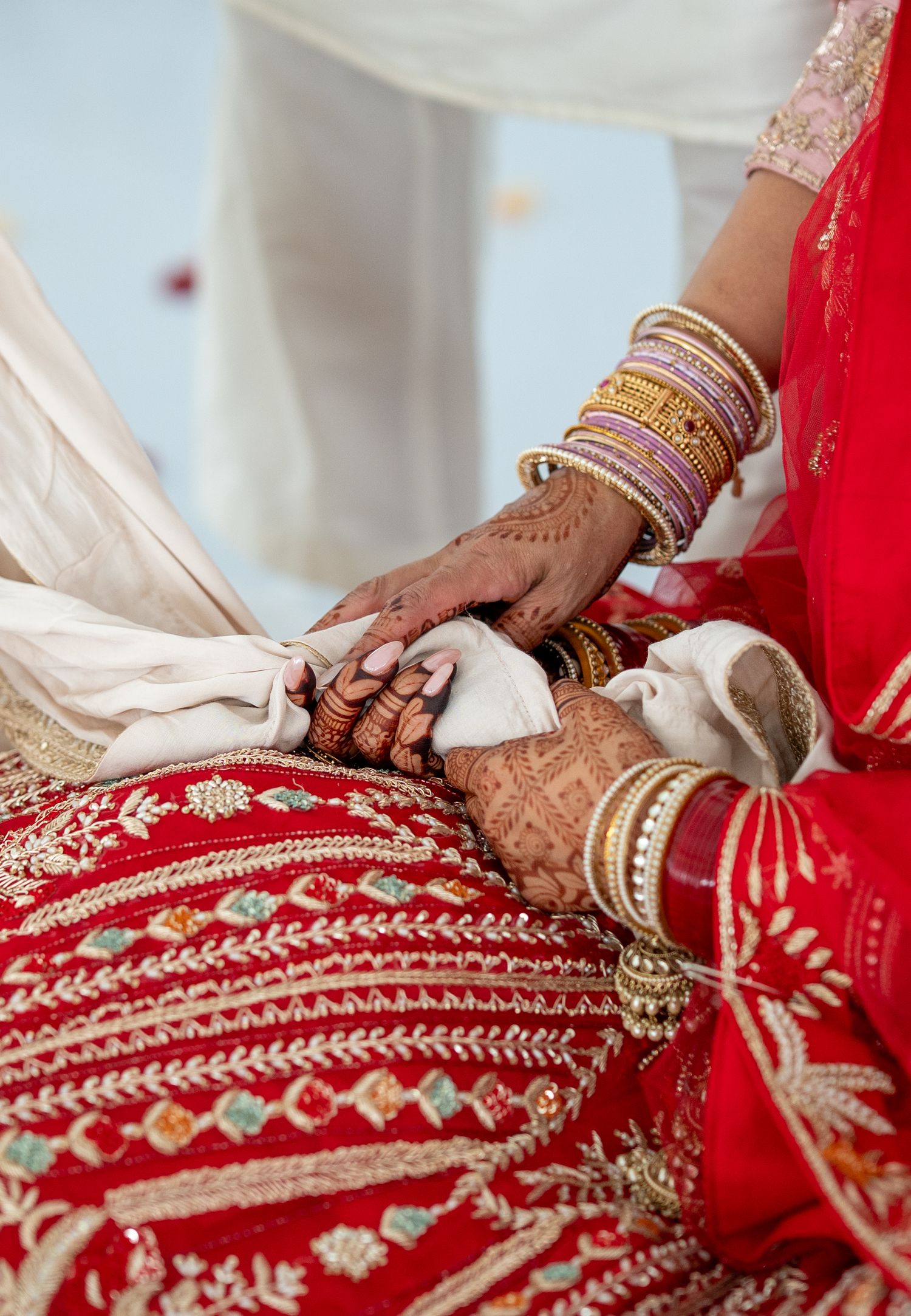 Detail shots of intricate embroidery on a red wedding lehenga with gold accents.