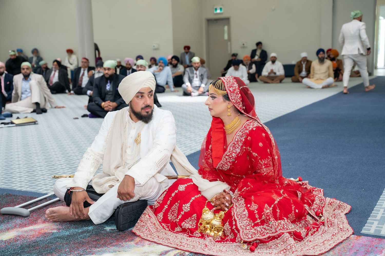 Traditional Sikh wedding ceremony with guests seated on floor during religious proceedings.