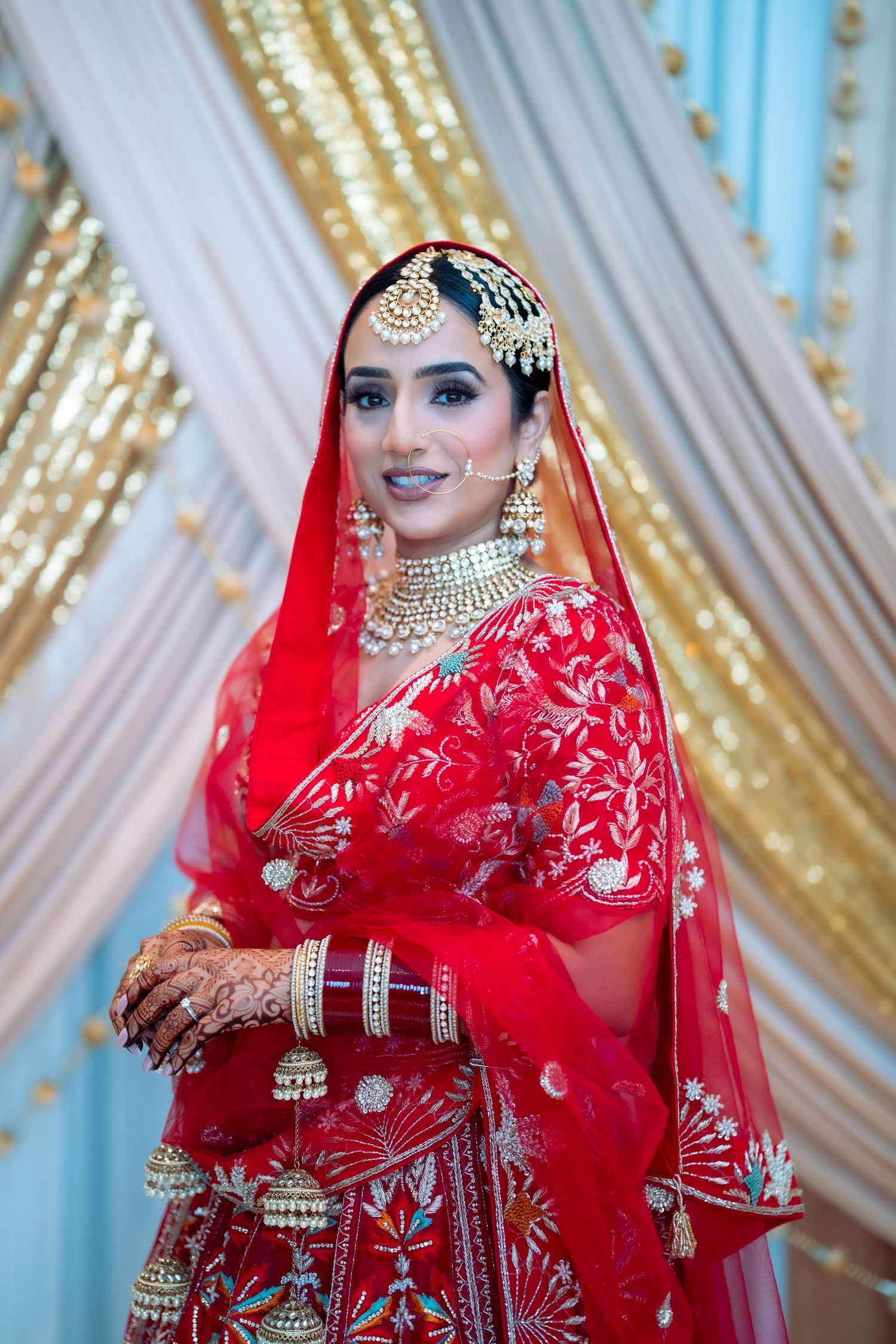 Close-up shots of bride wearing ornate gold jewelry and red embroidered wedding attire with veil.