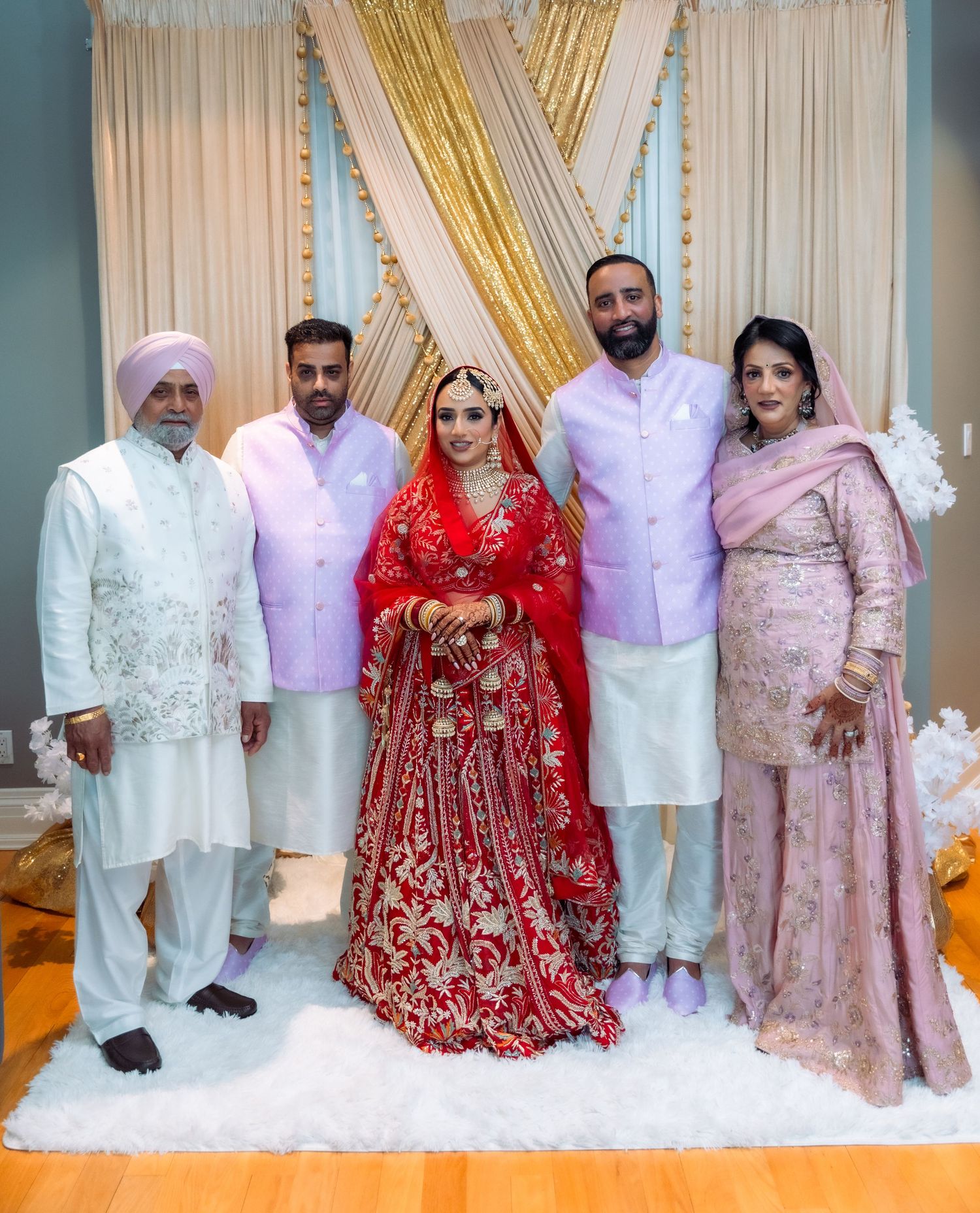 Family group photo at South Asian wedding with traditional white and red formal attire.