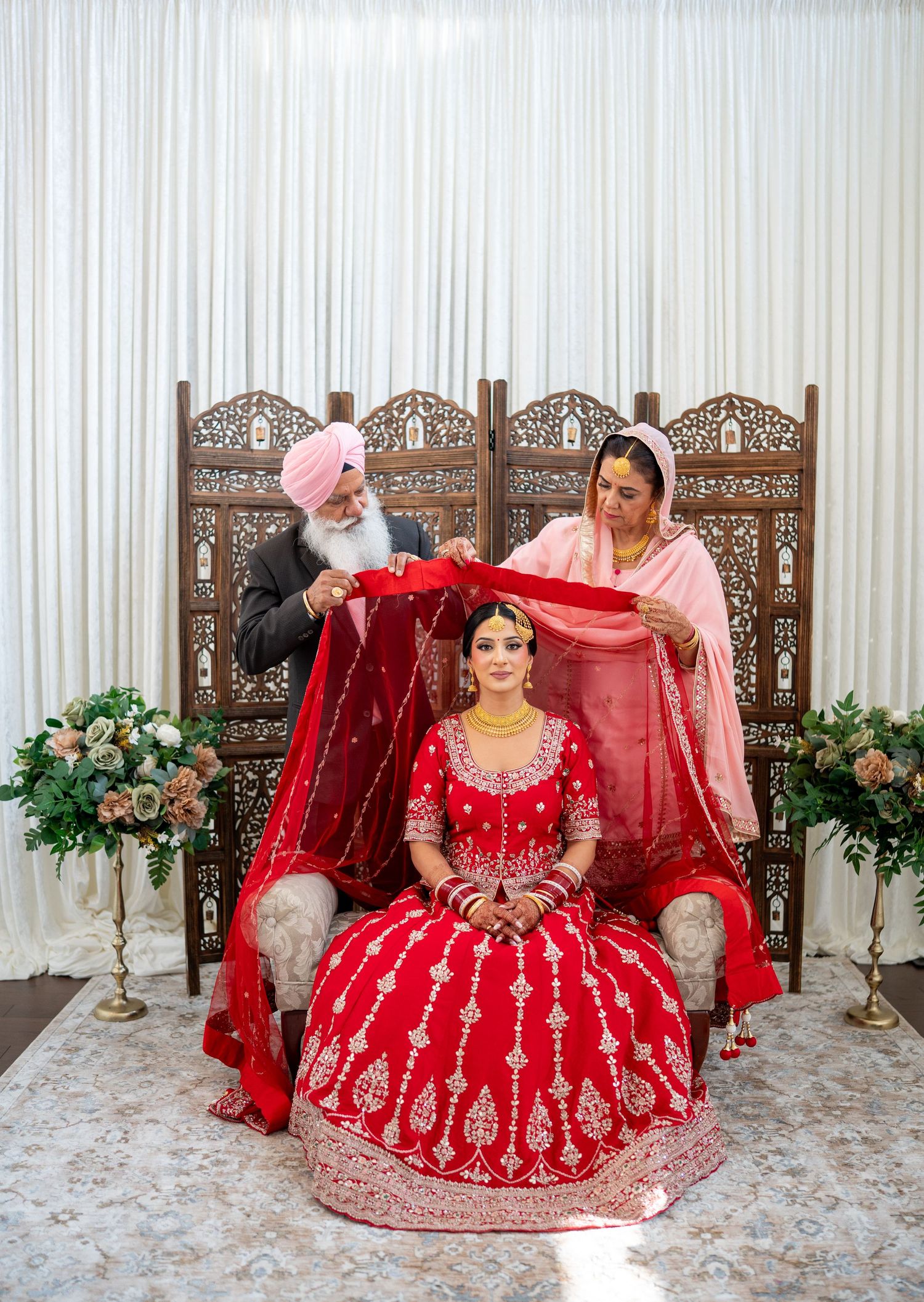 A stunning red bridal lehenga with intricate embroidery displayed in multiple poses against an elegant backdrop.