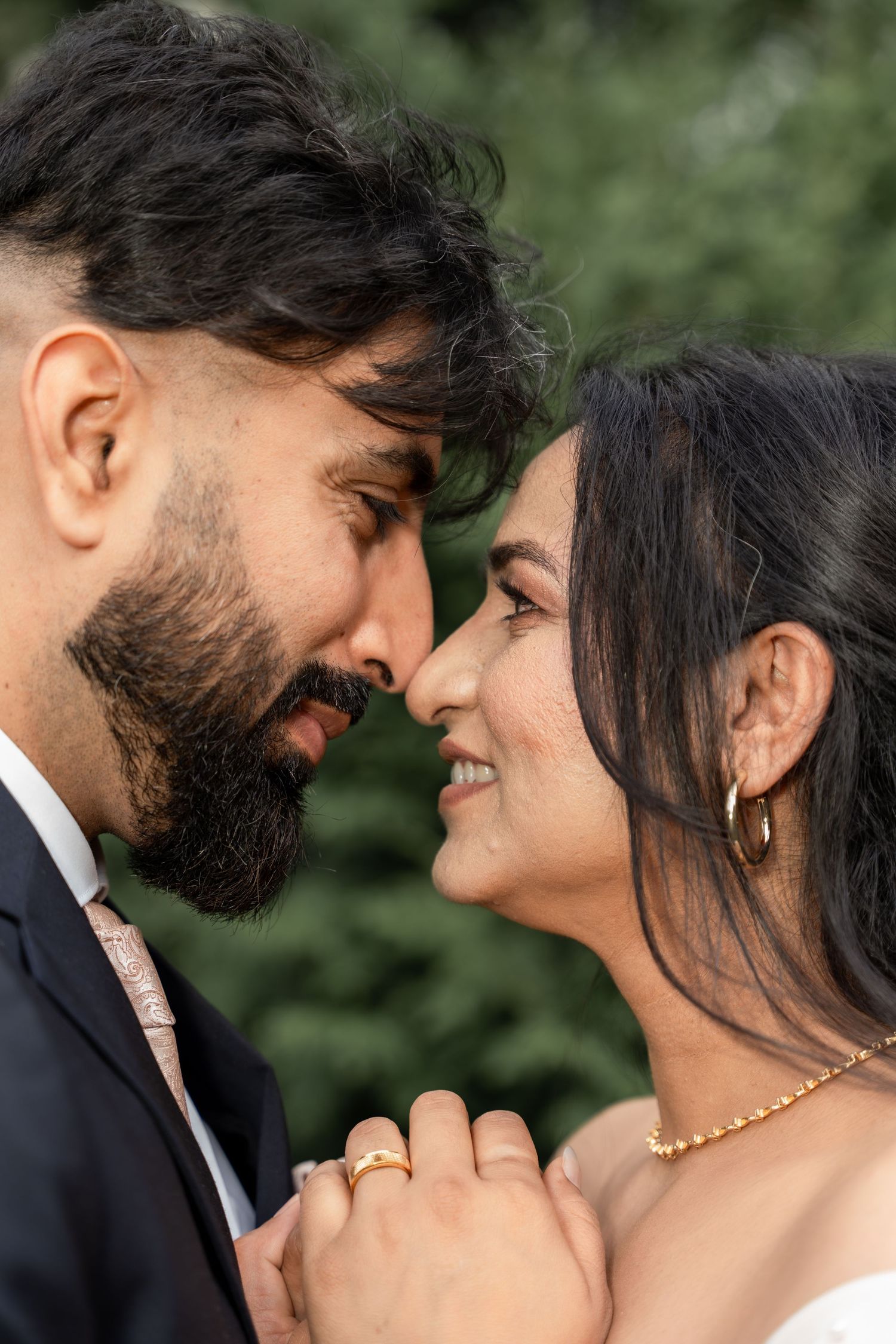 A romantic wedding couple sharing intimate moments in a garden setting with soft natural lighting and greenery.