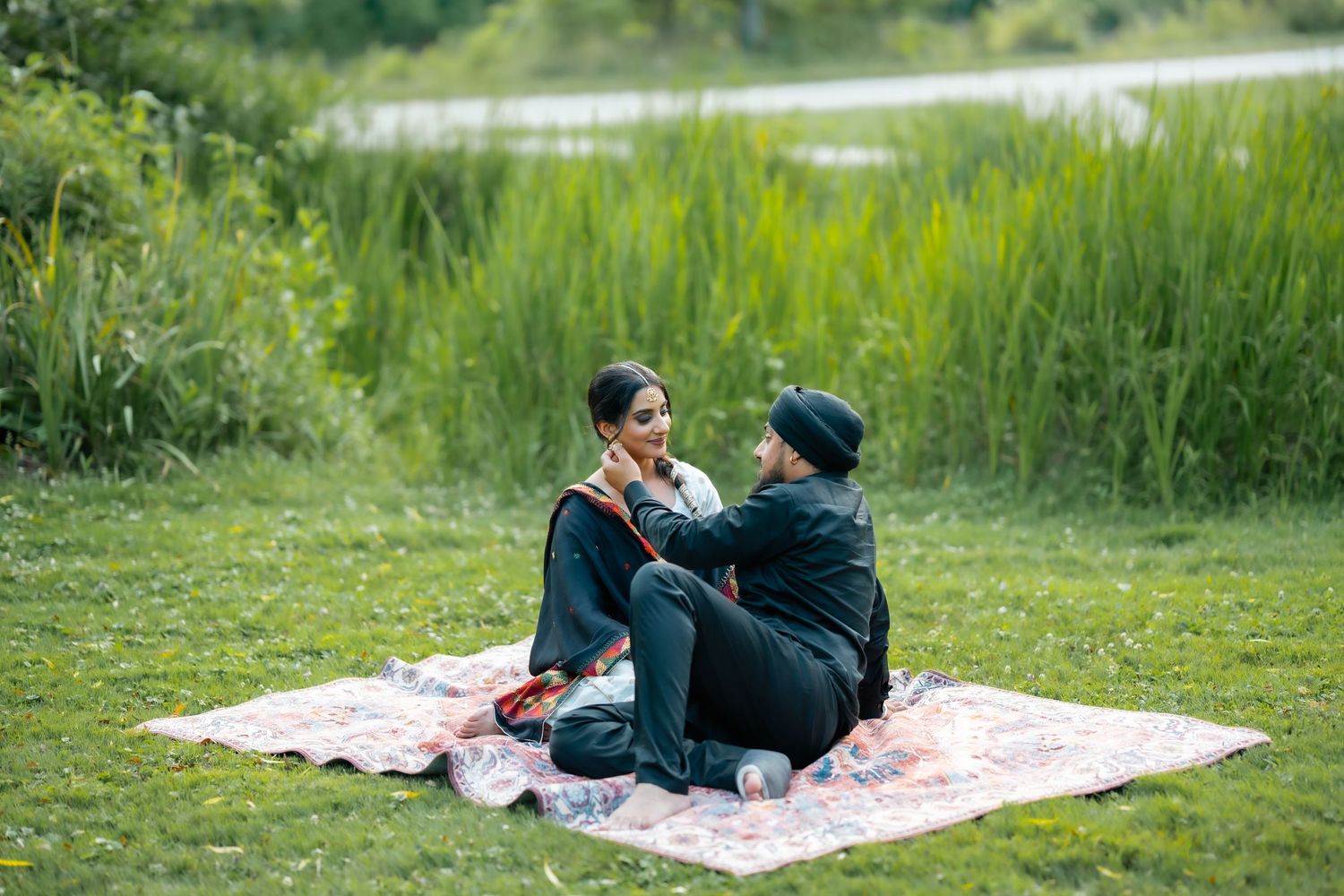 People enjoying a romantic picnic on a blanket in a lush green meadow on a sunny summer day.