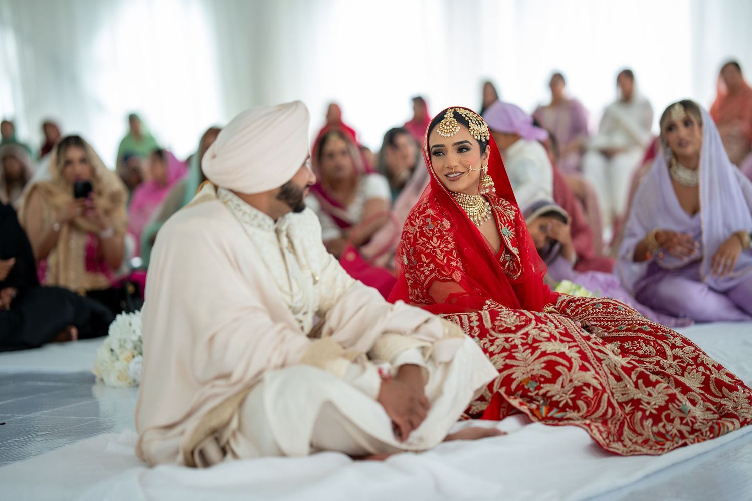 A traditional Indian wedding ceremony showing a couple performing rituals in red and white attire during their celebration.