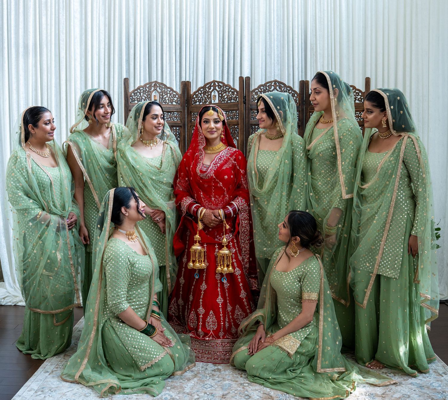 Bridesmaids in matching mint green traditional outfits pose together for formal wedding photos.