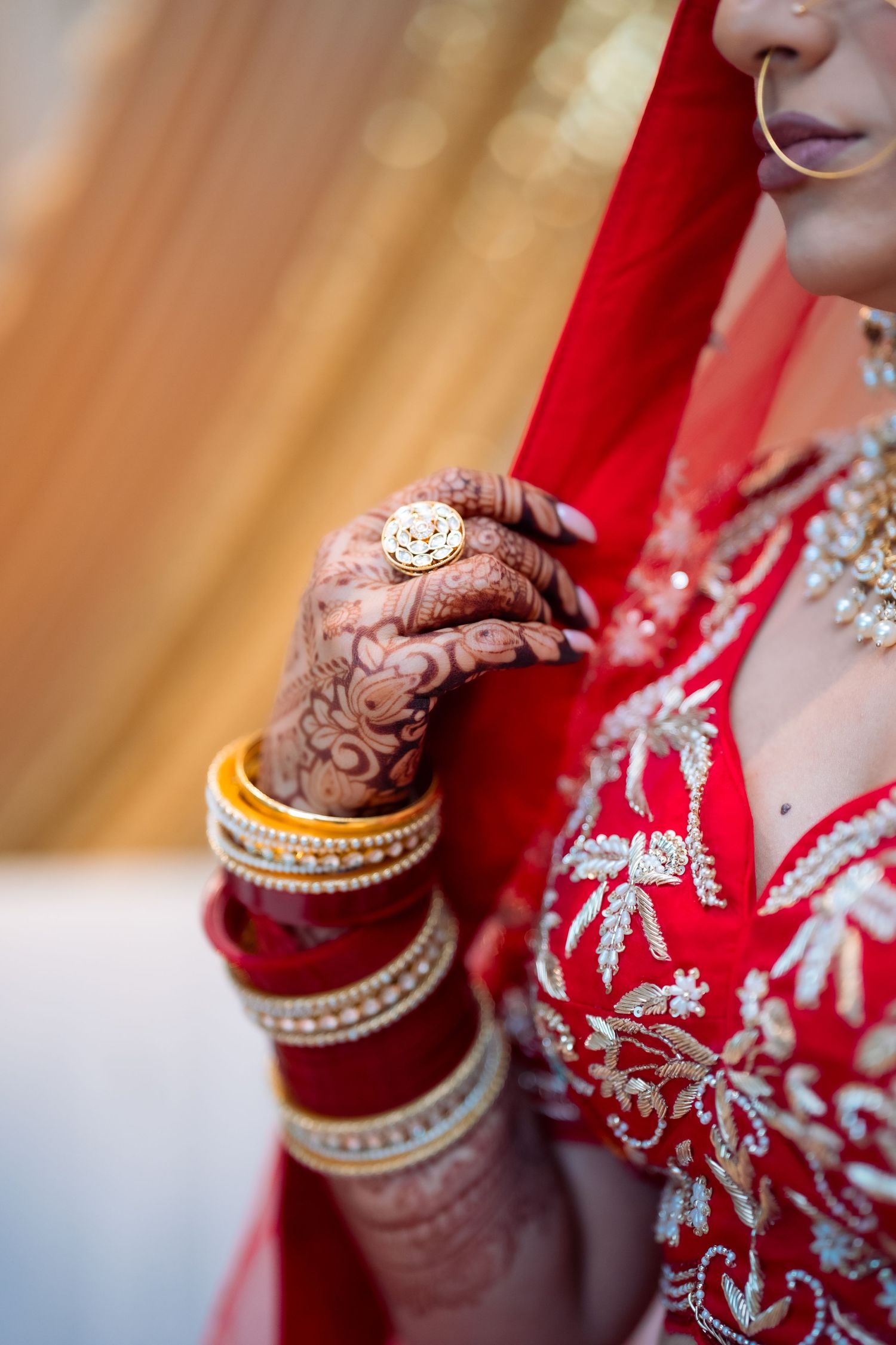 Close-up detail of traditional Indian bridal jewelry and red embroidered clothing with silver accents.