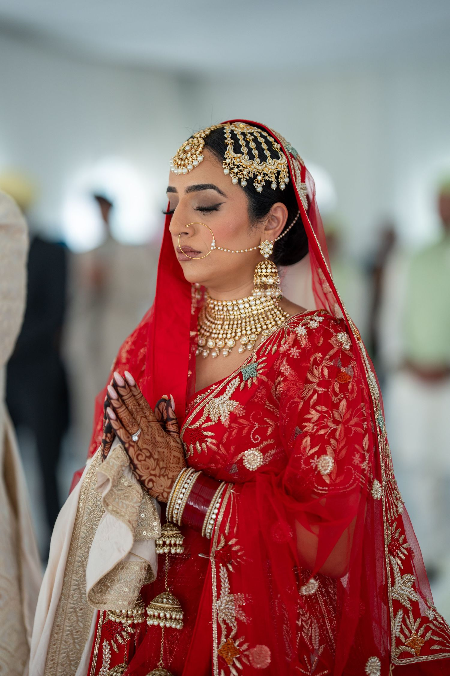 Traditional wedding ceremony with bride in red embroidered lehenga and gold jewelry.