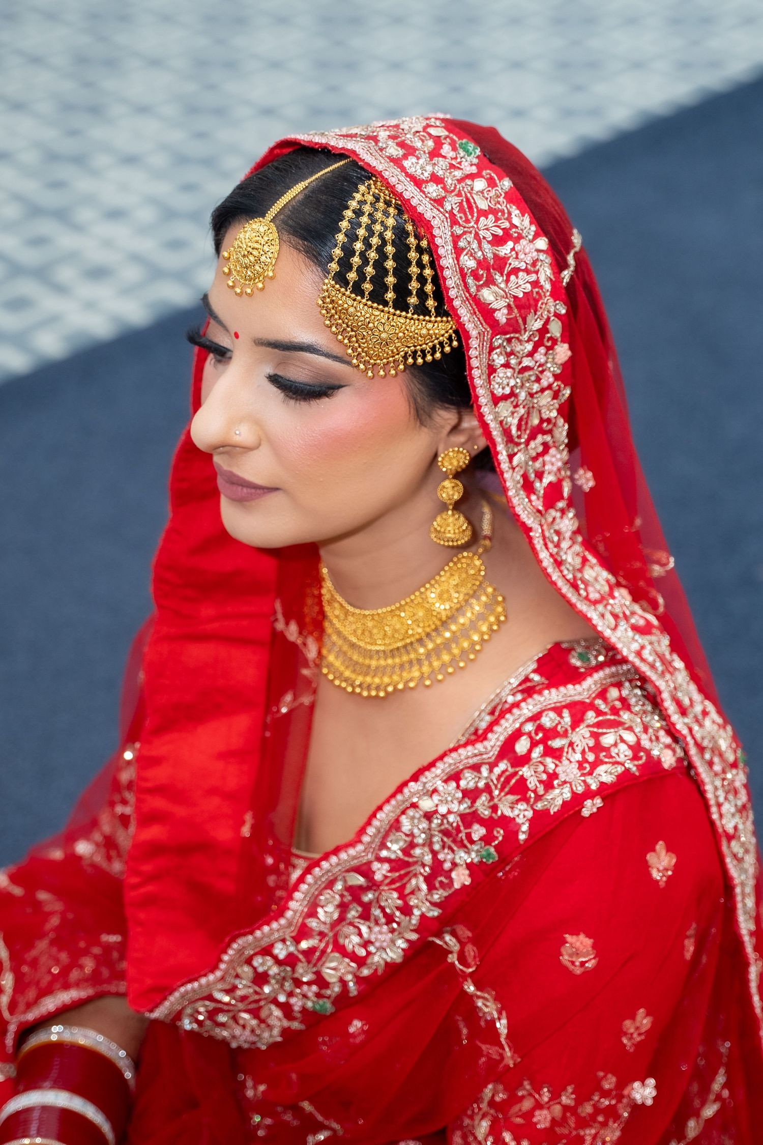 Traditional Indian bridal jewelry and red embroidered veil with intricate gold details.