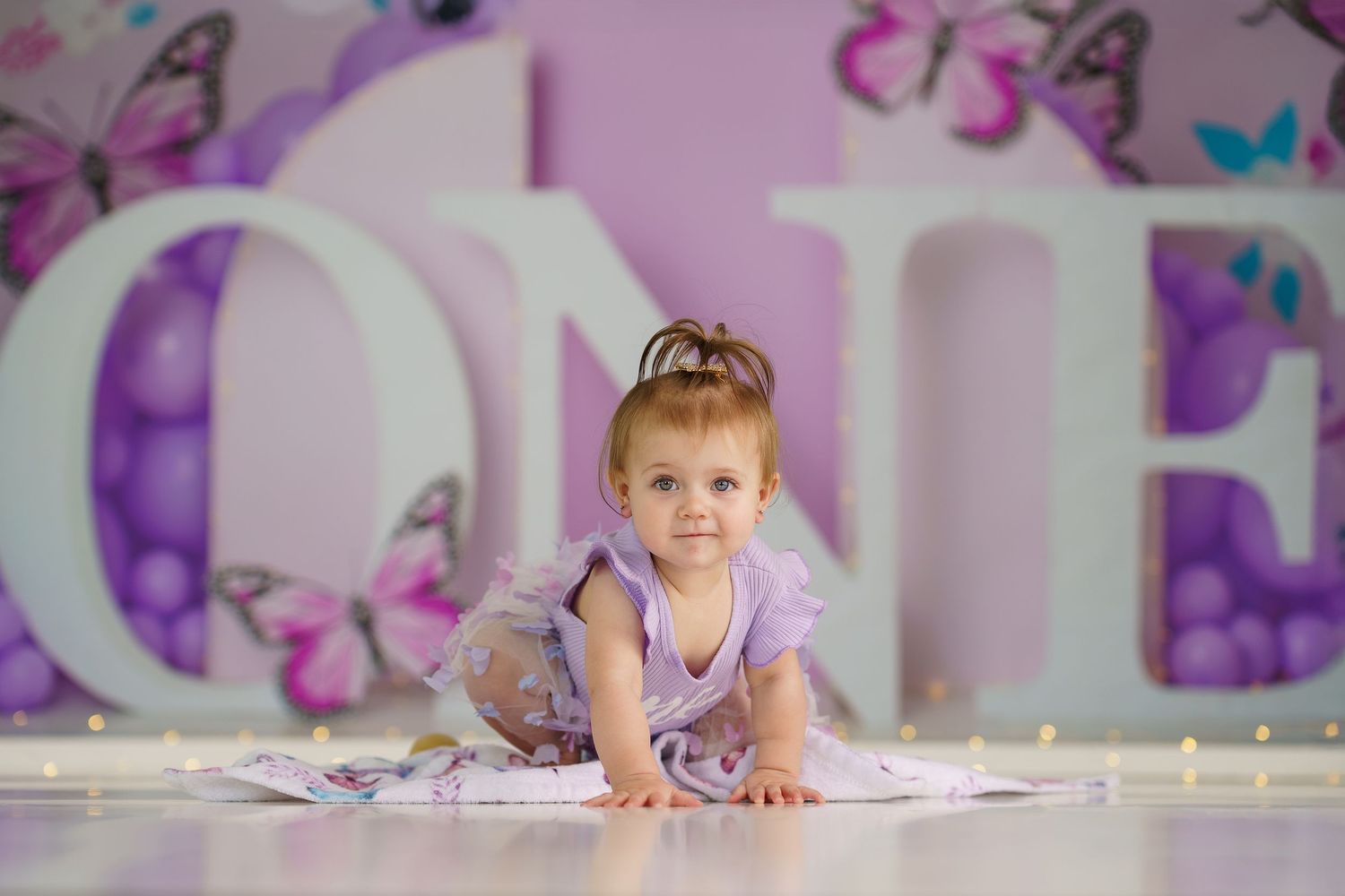 Purple studio setting with butterfly motifs and string lights along the floor.