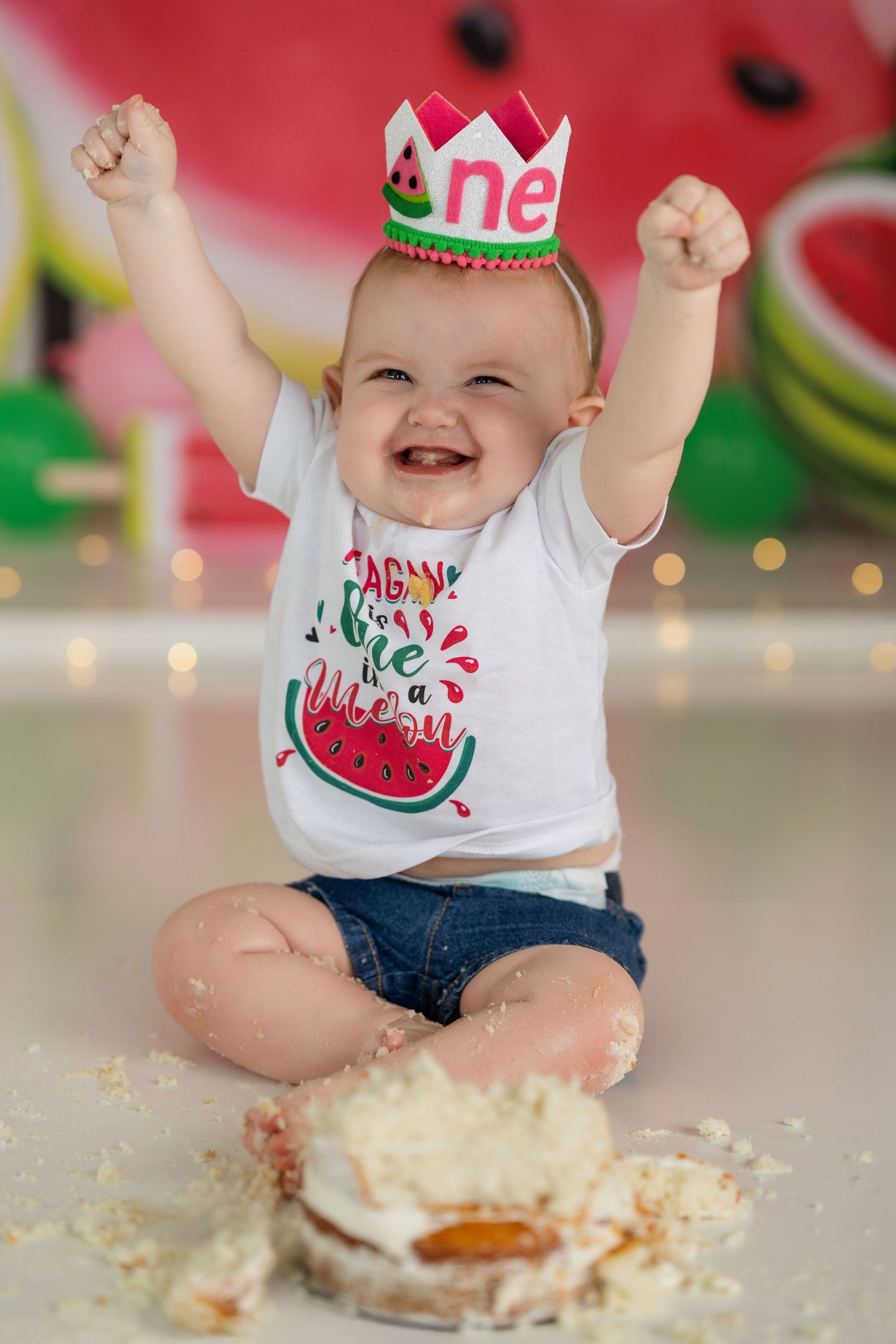 First birthday cake smash session with watermelon theme and white frosting scattered on floor.