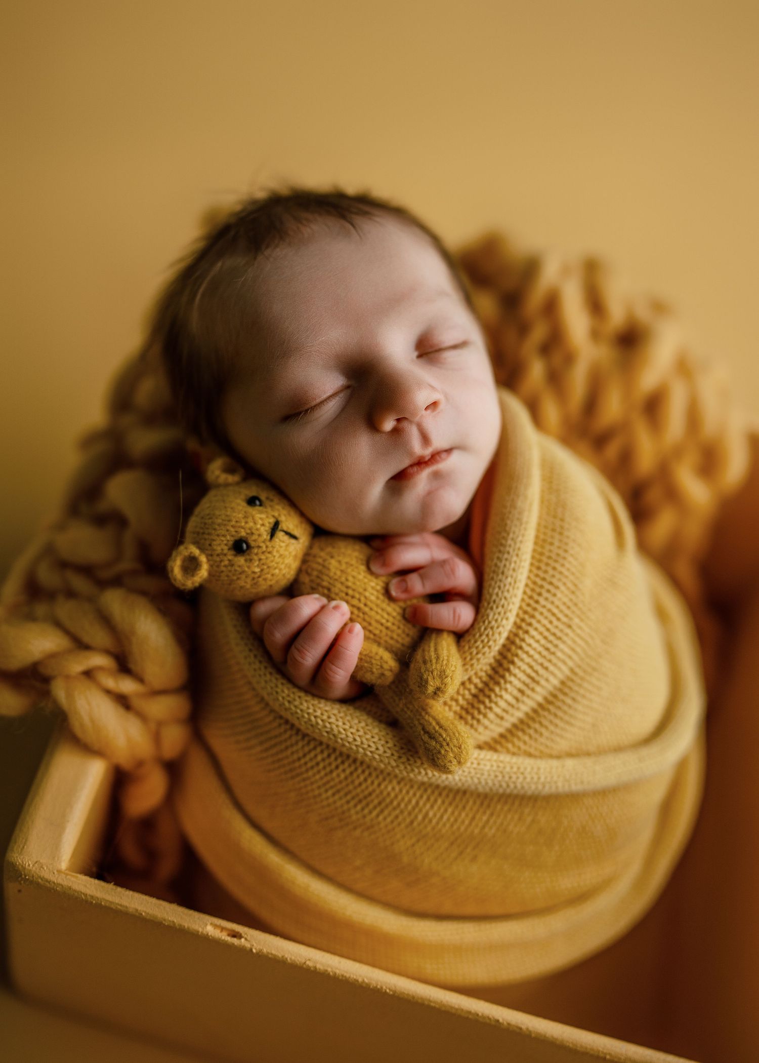 Artistic newborn photography sequence showing baby wrapped in yellow knit blanket.