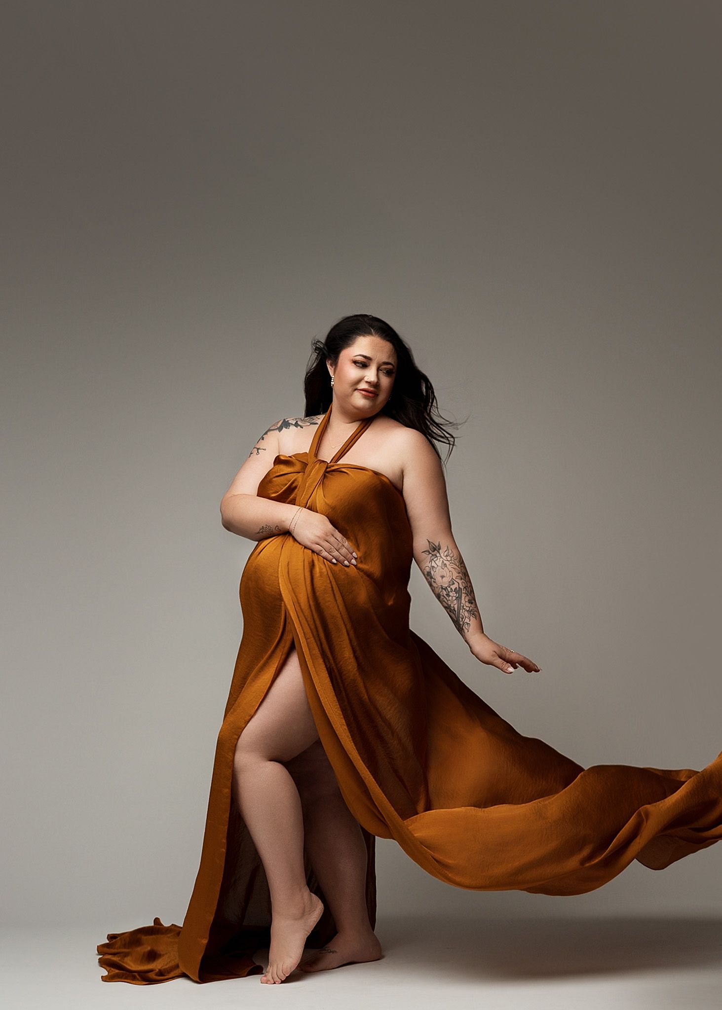 Elegant rust-colored flowing dress with thigh-high slit photographed in studio setting.