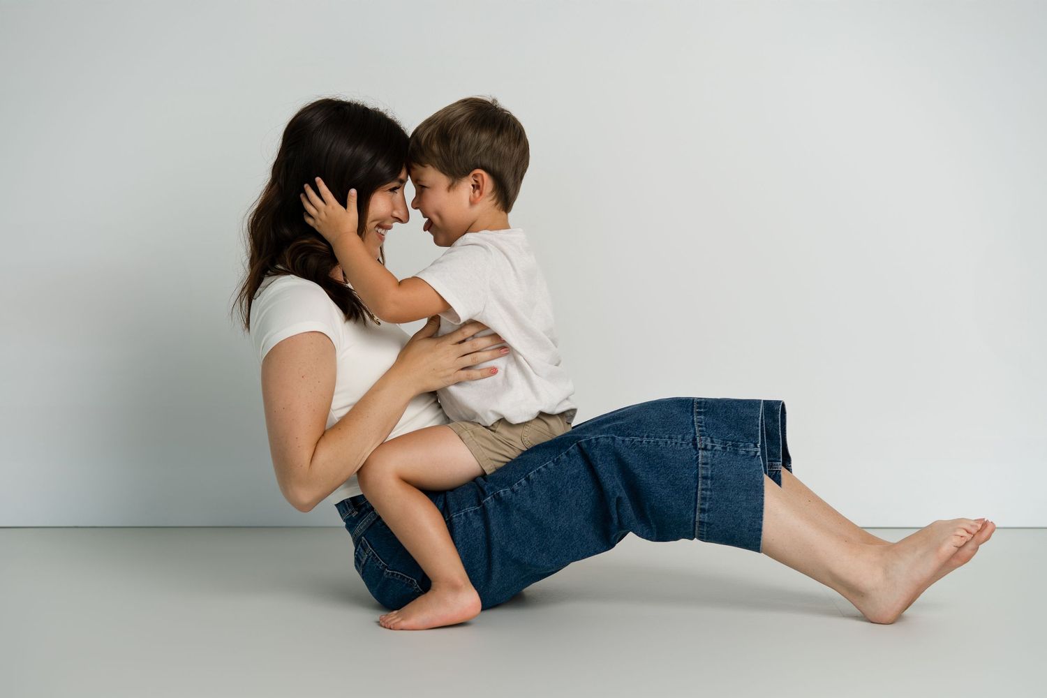 Casual portrait session against white background showing warm family interaction.