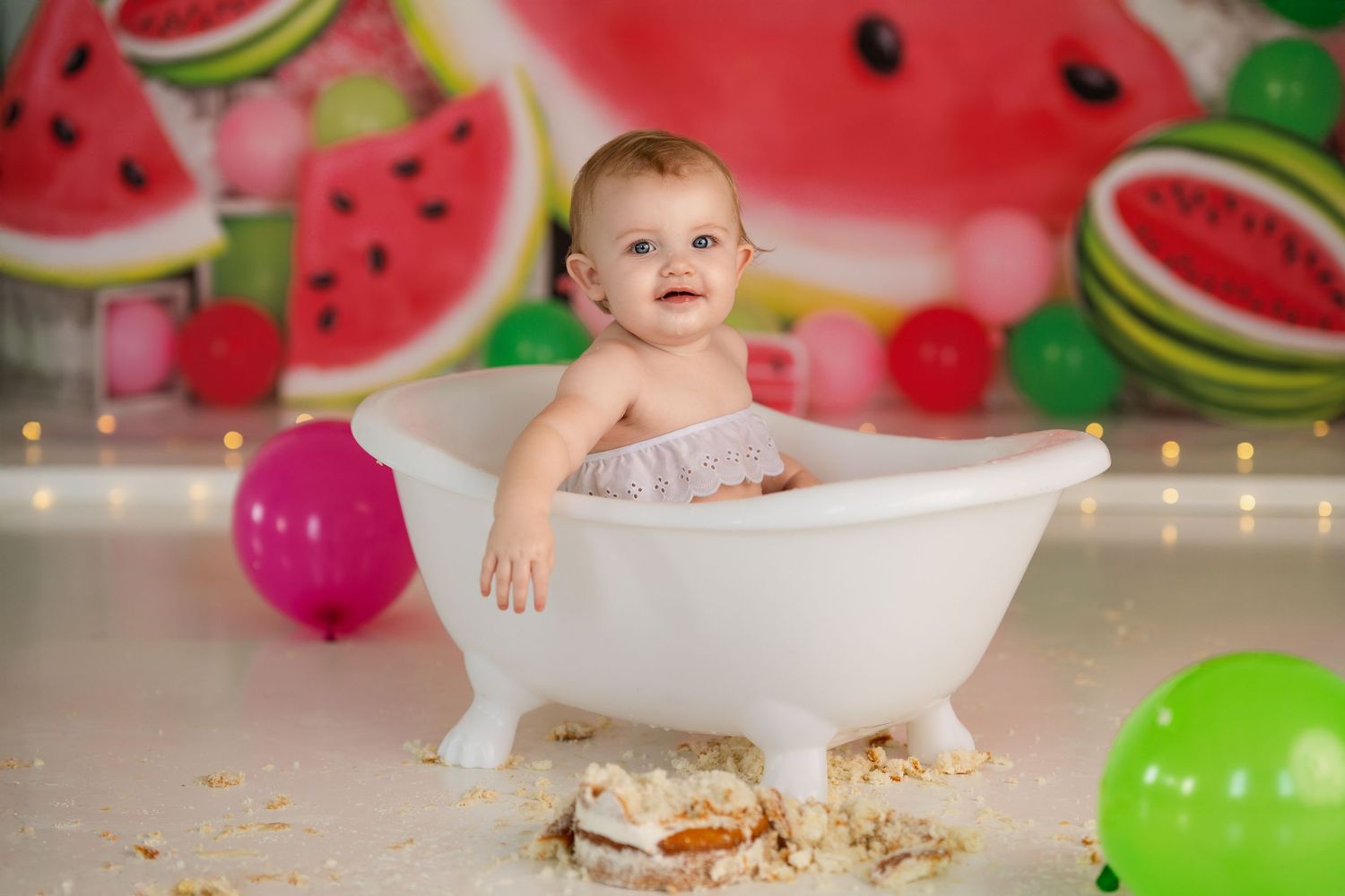 Birthday celebration setup with watermelon backdrop and white bathtub prop.