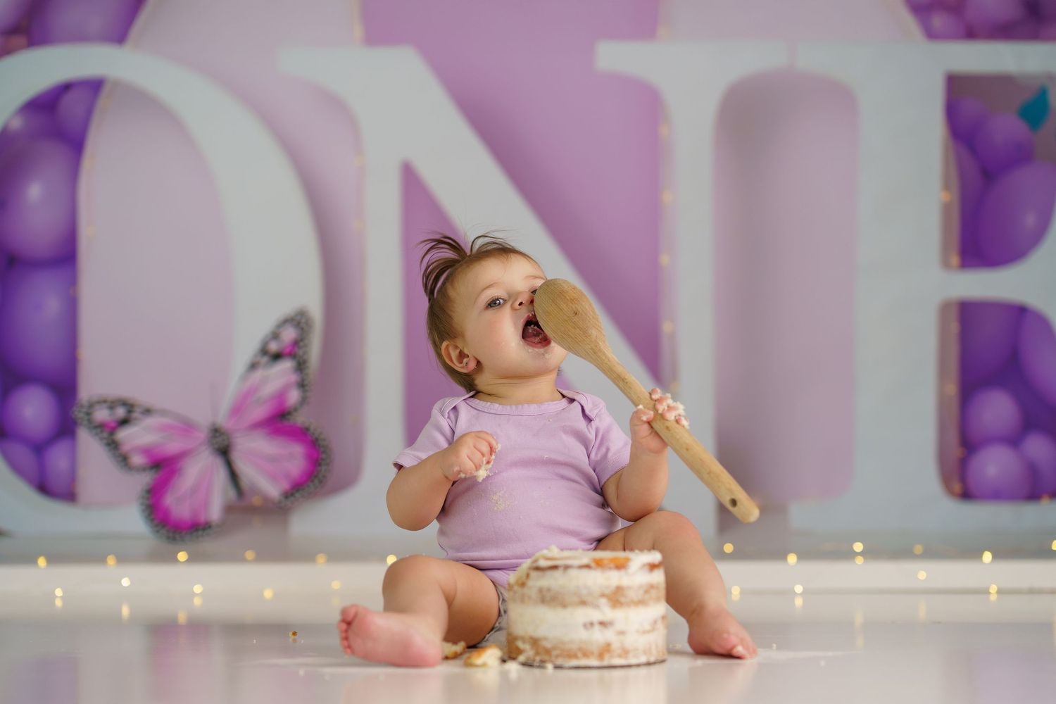 Whimsical purple photography setup with butterfly designs and floor lighting.