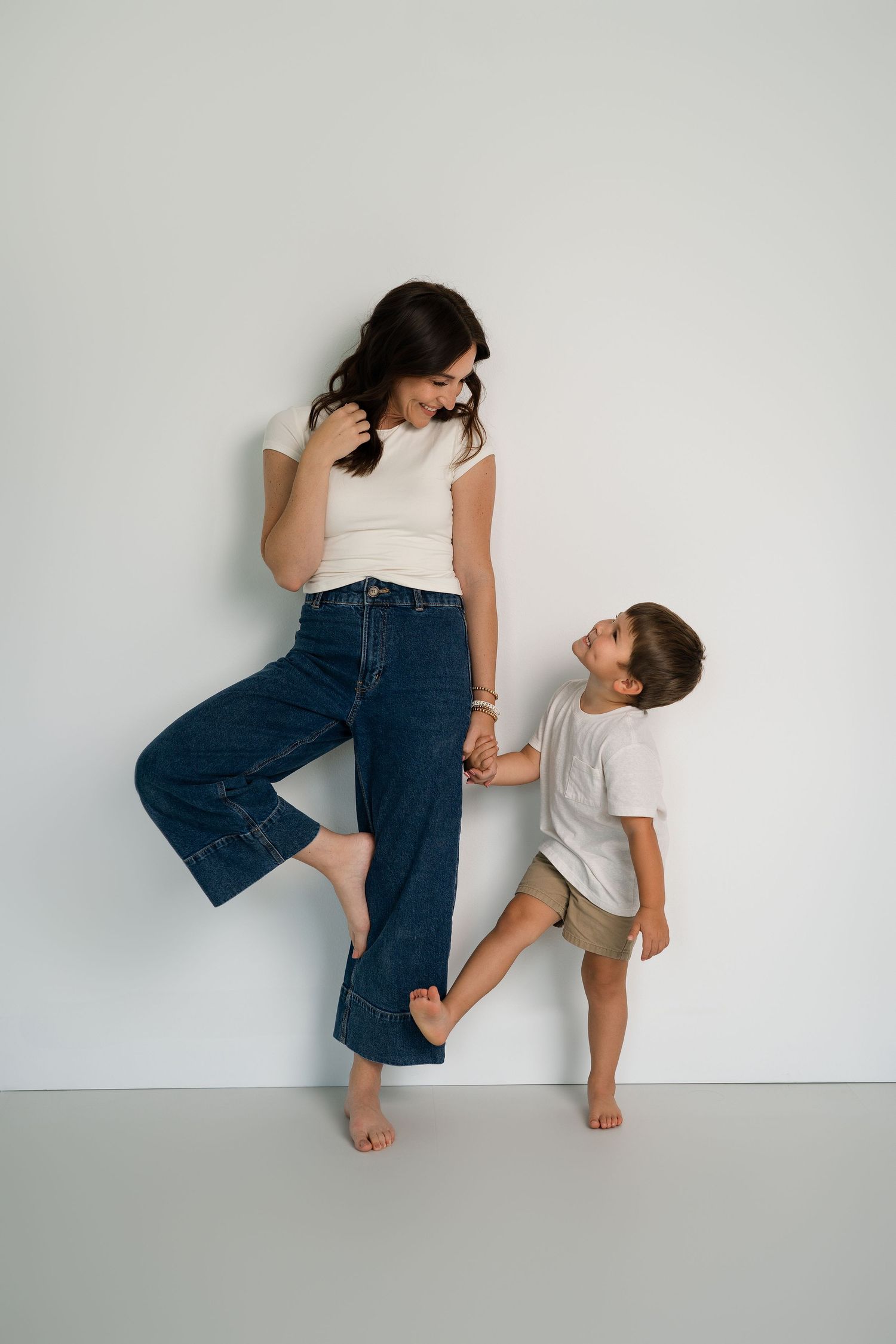 Playful interaction between two people wearing casual clothes against white wall.