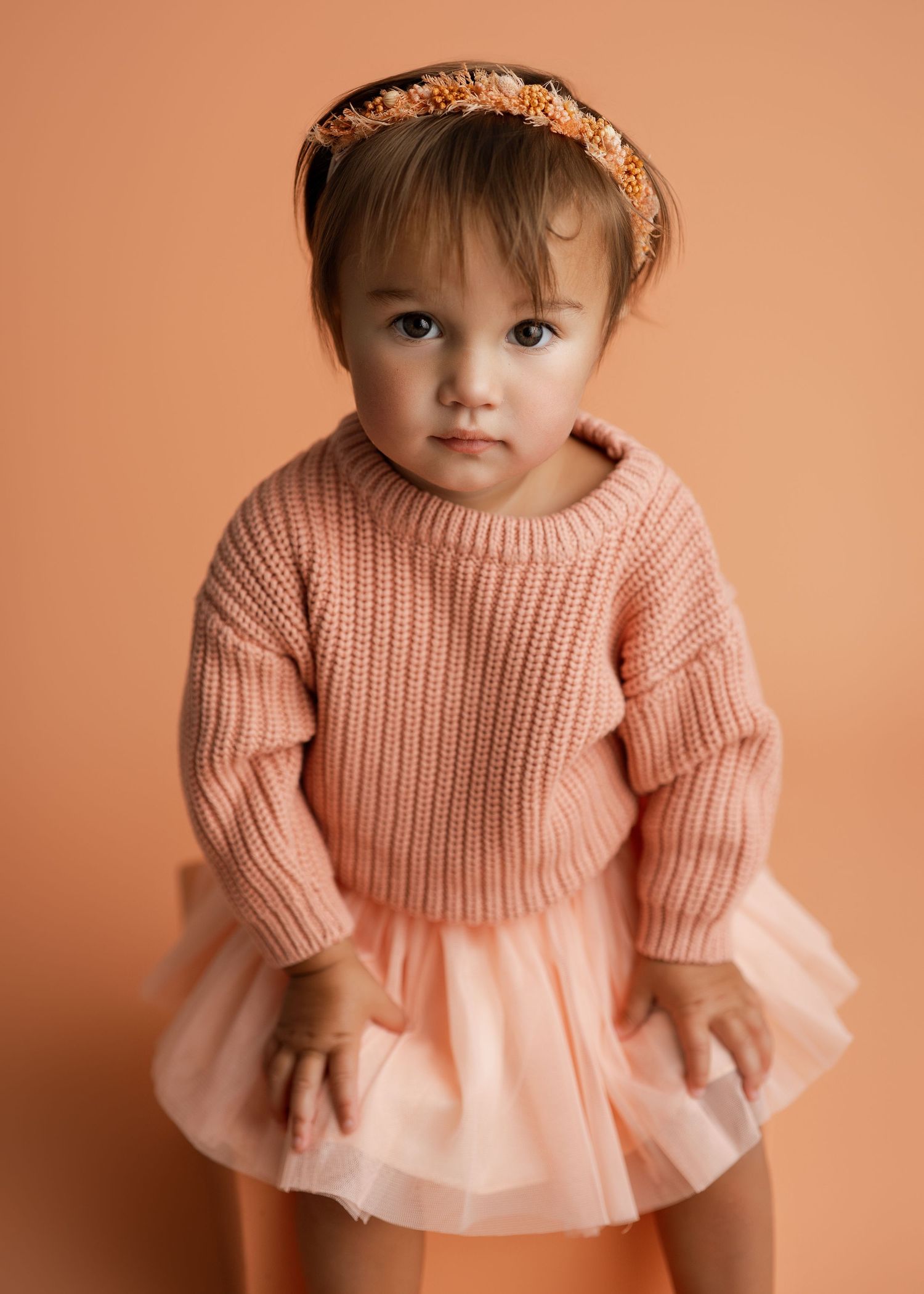 Sweet portrait series in a peach knit sweater with tulle skirt against peachy background.