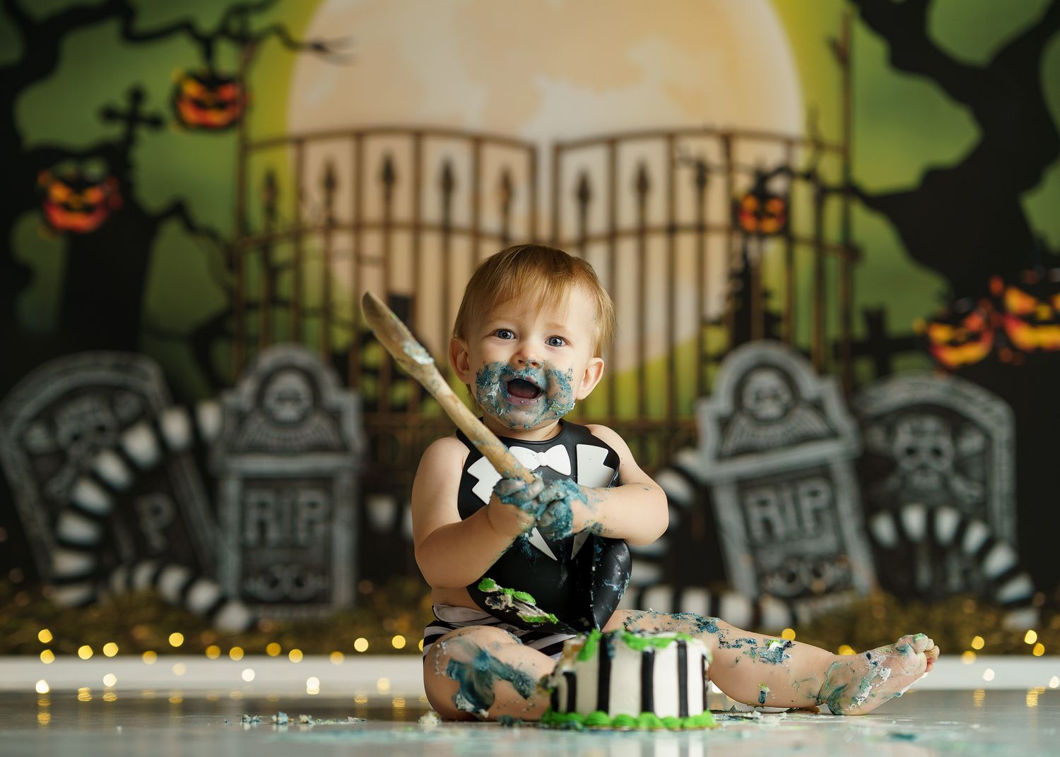 Halloween themed photo setup with decorative backdrop featuring pumpkins and cemetery gates.