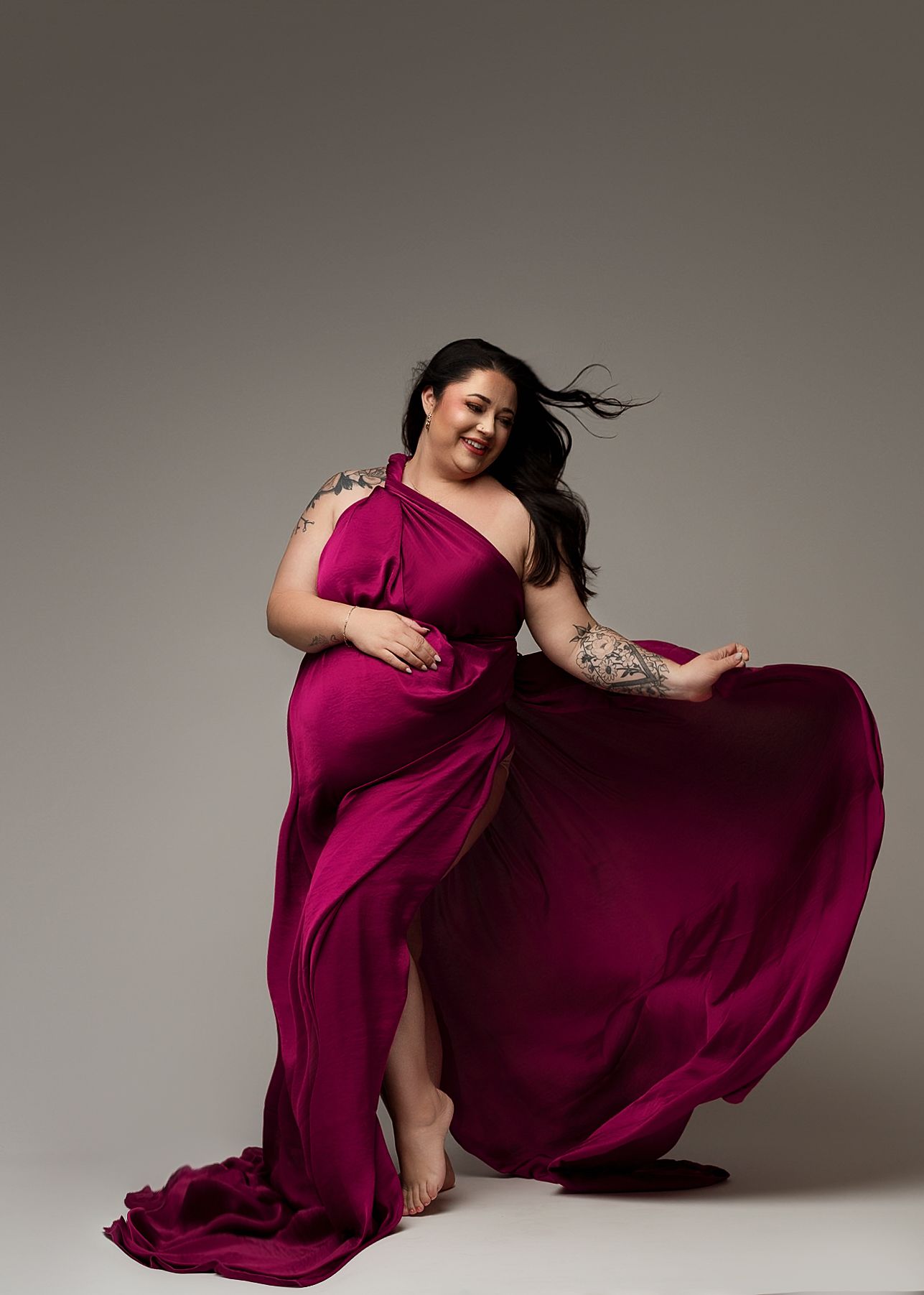 Dynamic poses in burgundy flowing dress showing movement against studio background.