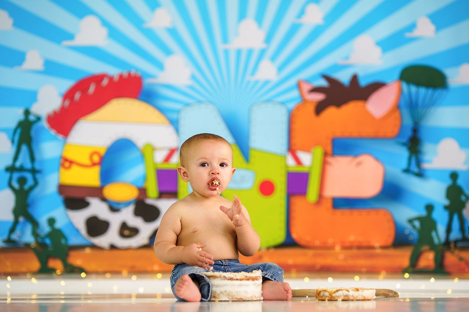 Festive cake smash photo setup with vibrant blue background and playful party decorations.