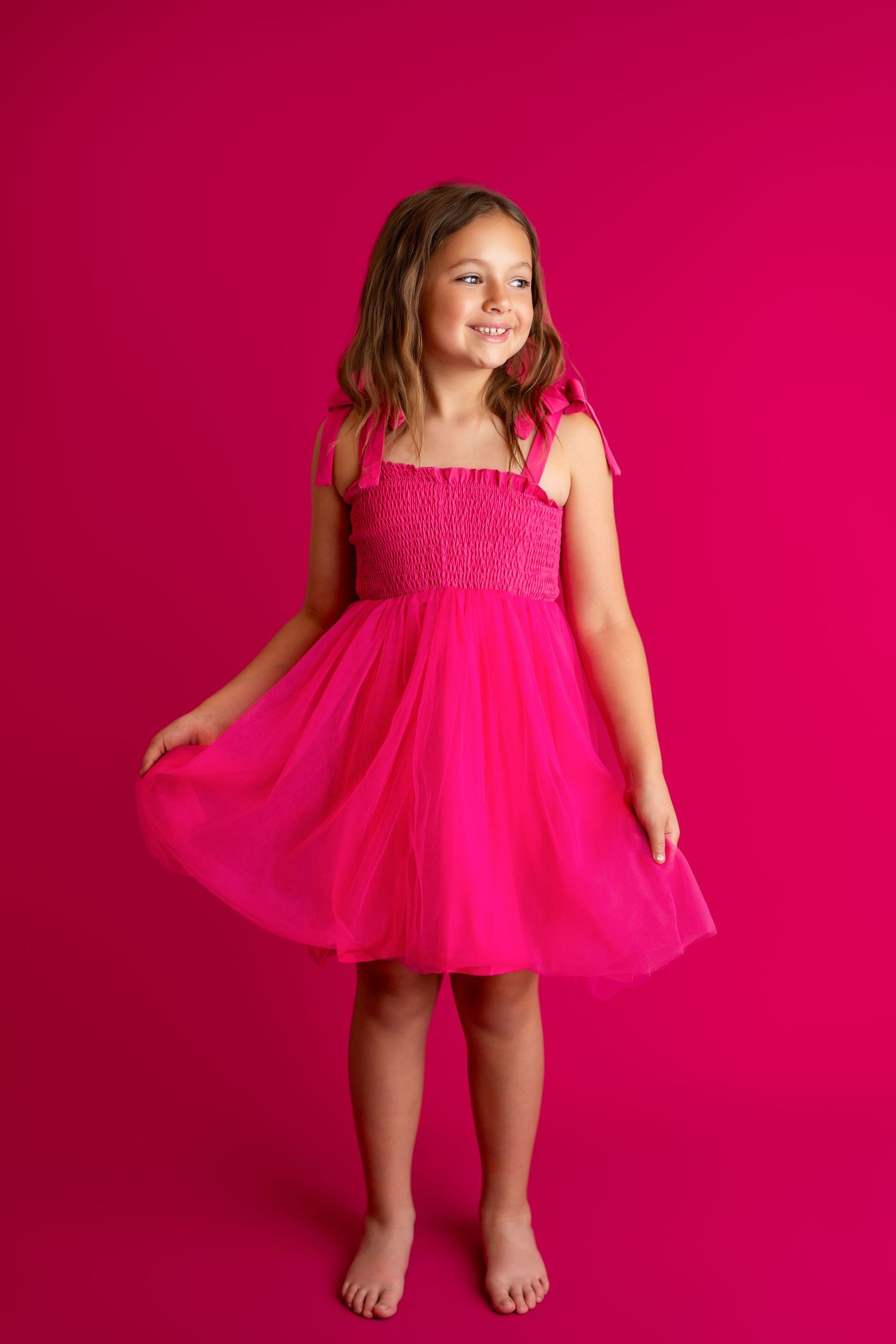 Energetic dance movements captured in bright pink dress against fuchsia backdrop.