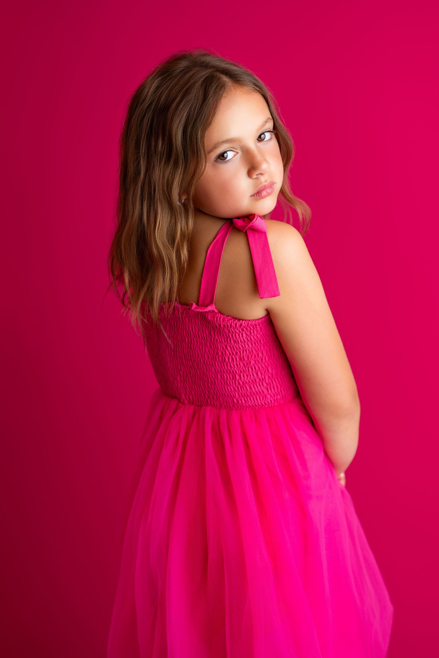 Dramatic dance poses captured in flowing pink dress against fuchsia background.