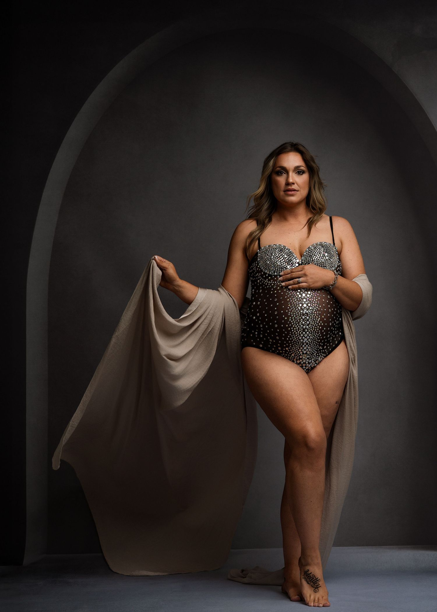 Artistic dance poses in silver bodysuit with flowing fabric against dark studio setting.