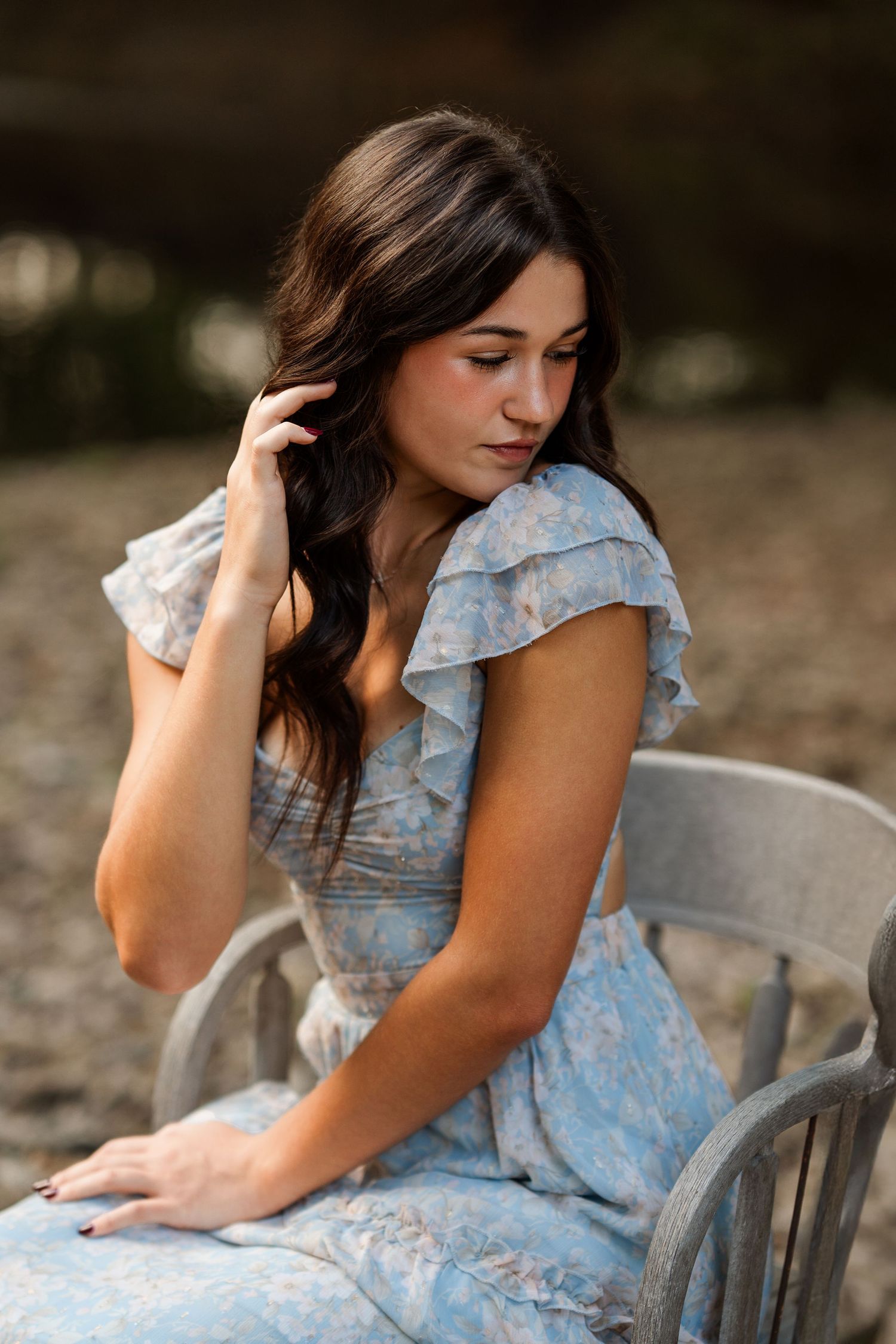 Soft portrait photography of someone in a ruffled blue dress sitting thoughtfully.