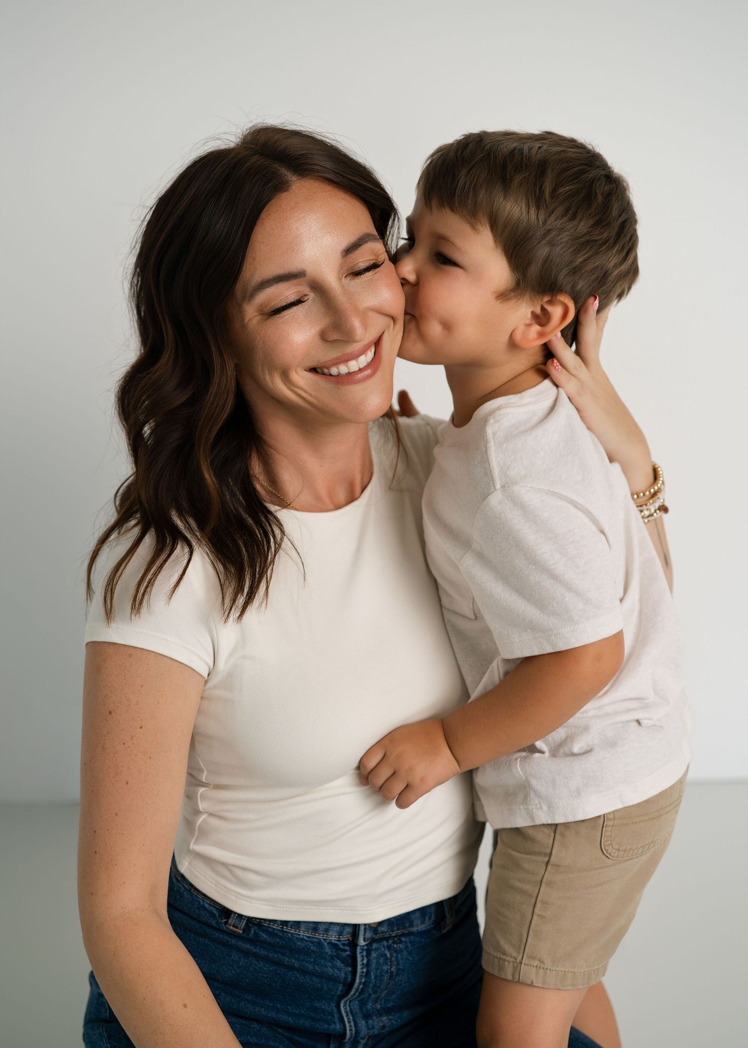 Sweet candid moments captured against white backdrop showing genuine affection.