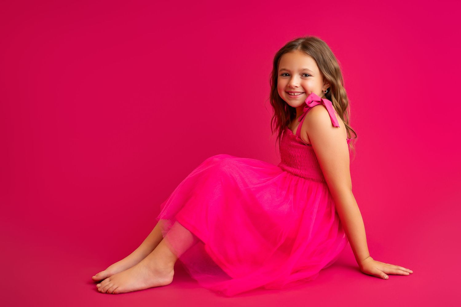 Graceful dance poses in flowing hot pink dress against vibrant studio background.