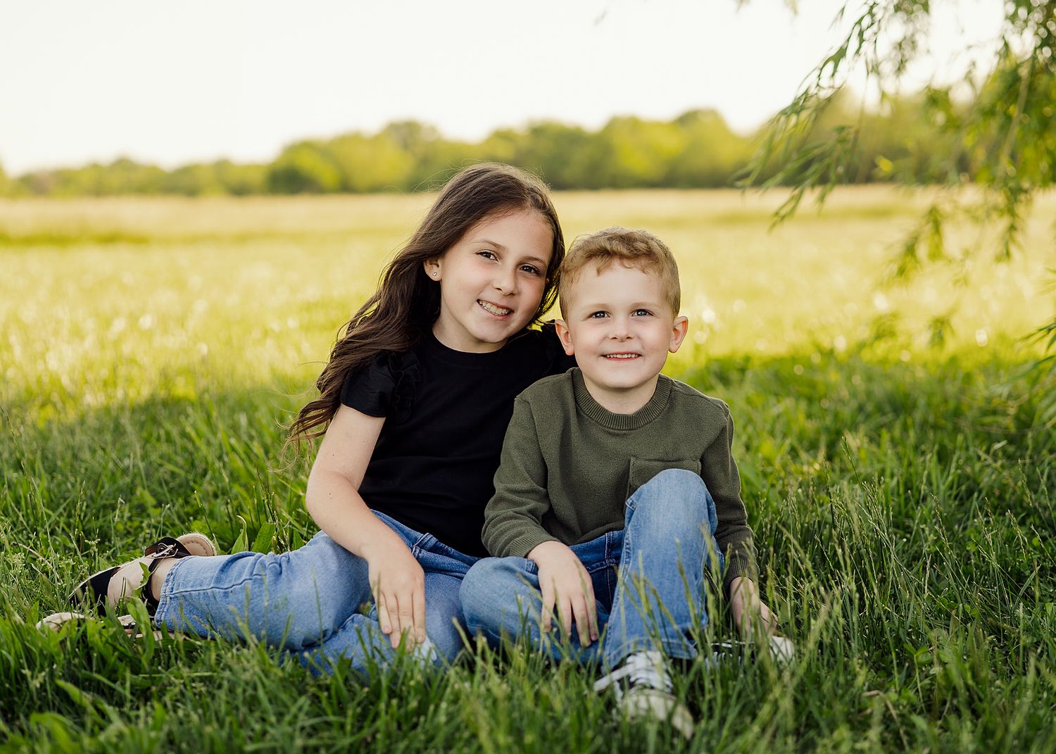 Mother and child sitting together in sunny meadow during golden hour.