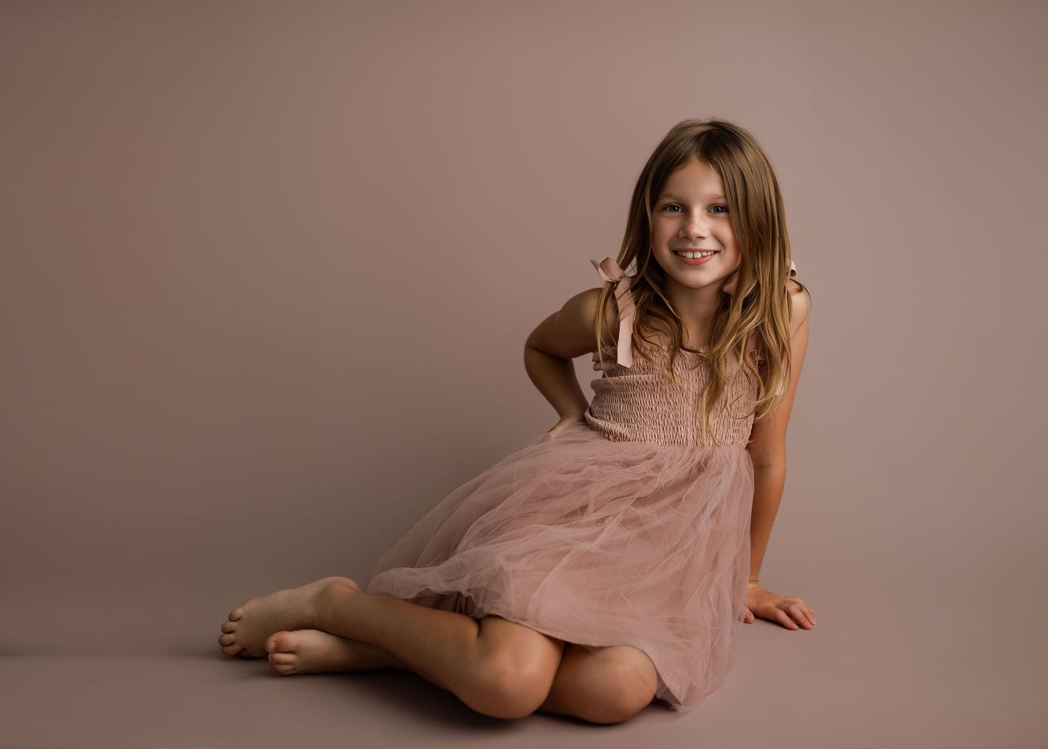 Studio portrait series showing young dancer in pink tulle dress against neutral backdrop.