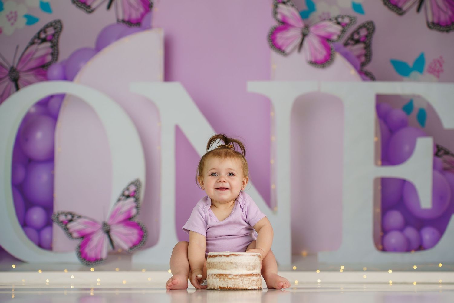 Enchanting purple photo studio with butterfly wall art and string lights.