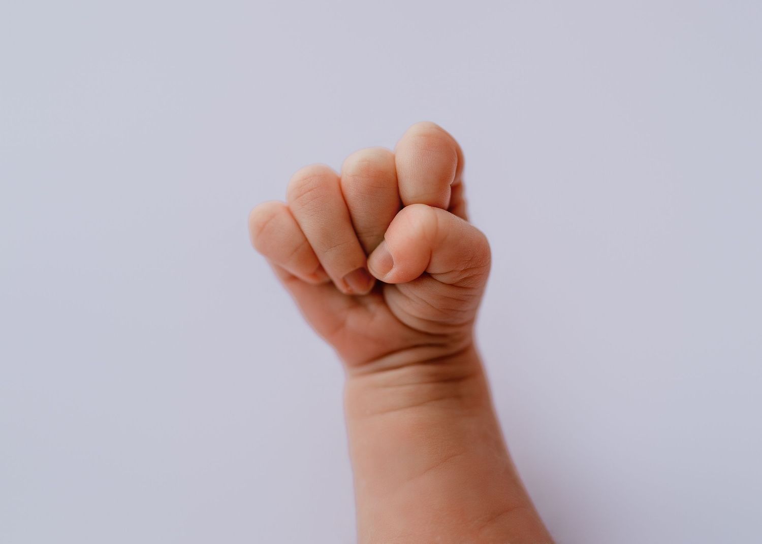 Artistic macro shots of tiny baby fists against white backdrop.