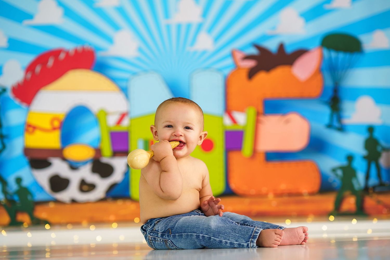Joyful baby sitting on floor against colorful cartoon backdrop with sunburst pattern.