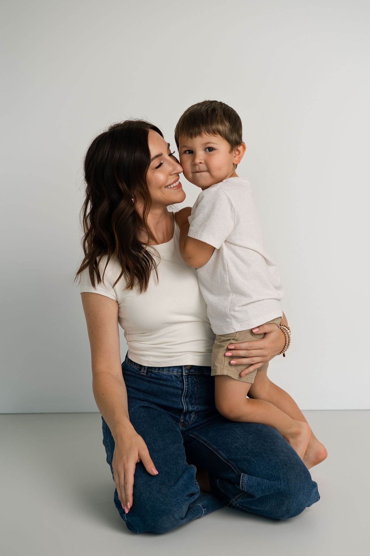 Two people in white and denim share affectionate poses against minimal background.