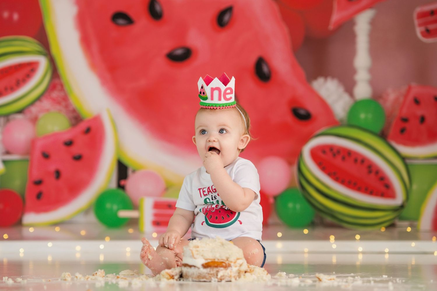 Festive watermelon-themed photo with decorative crown and cake setup.