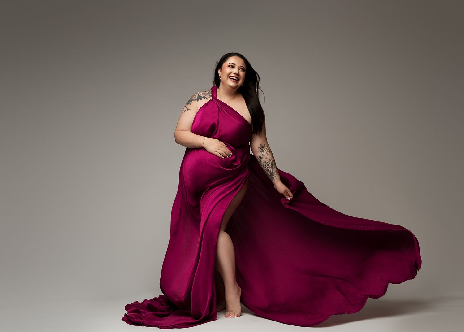 Luxurious magenta evening gown with sweeping train photographed in studio setting.