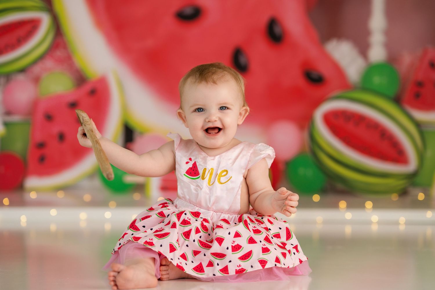 Joyful celebration photo with watermelon-themed backdrop and heart-patterned outfit.