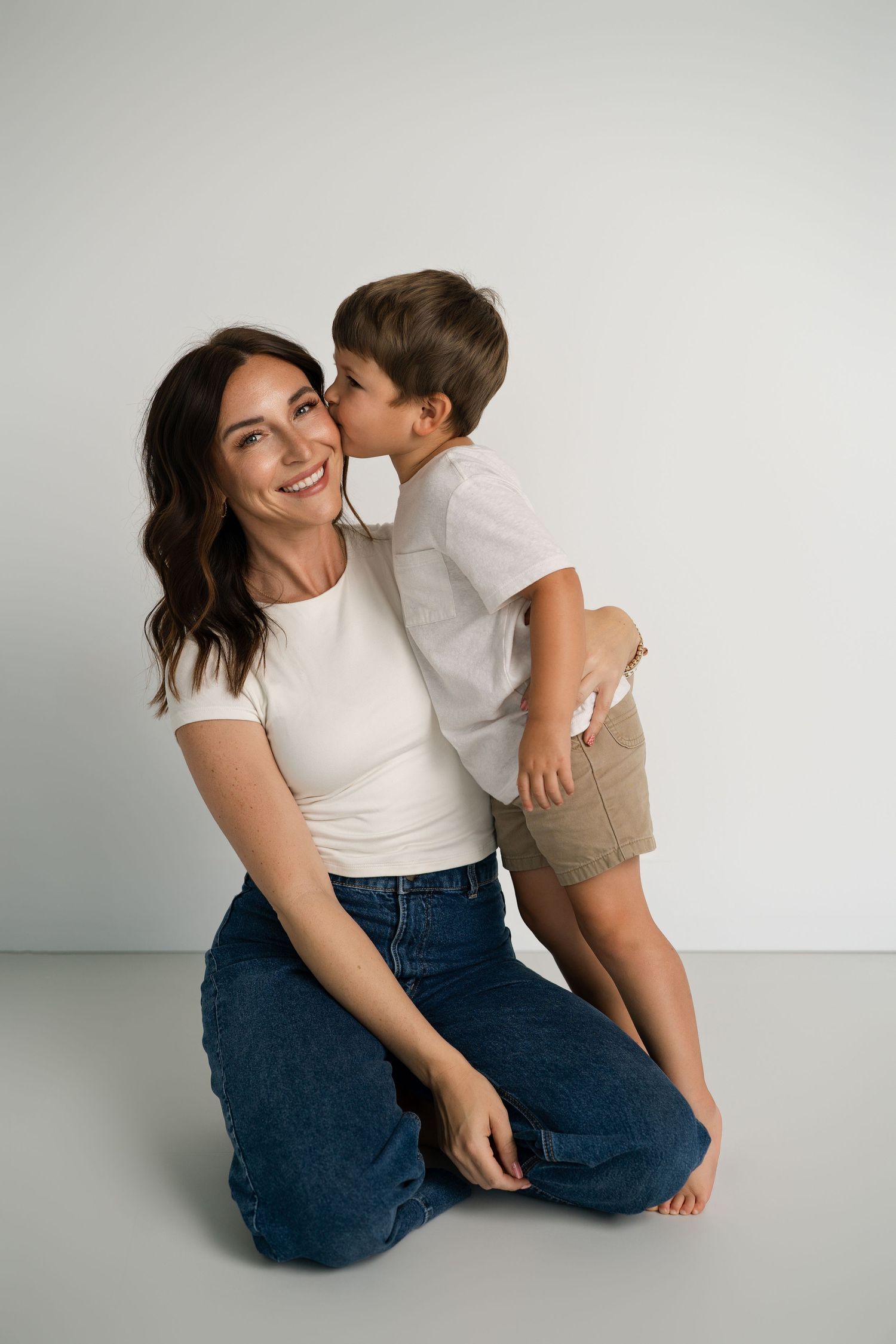 Candid moment of two people in casual wear sharing laughter against white background.